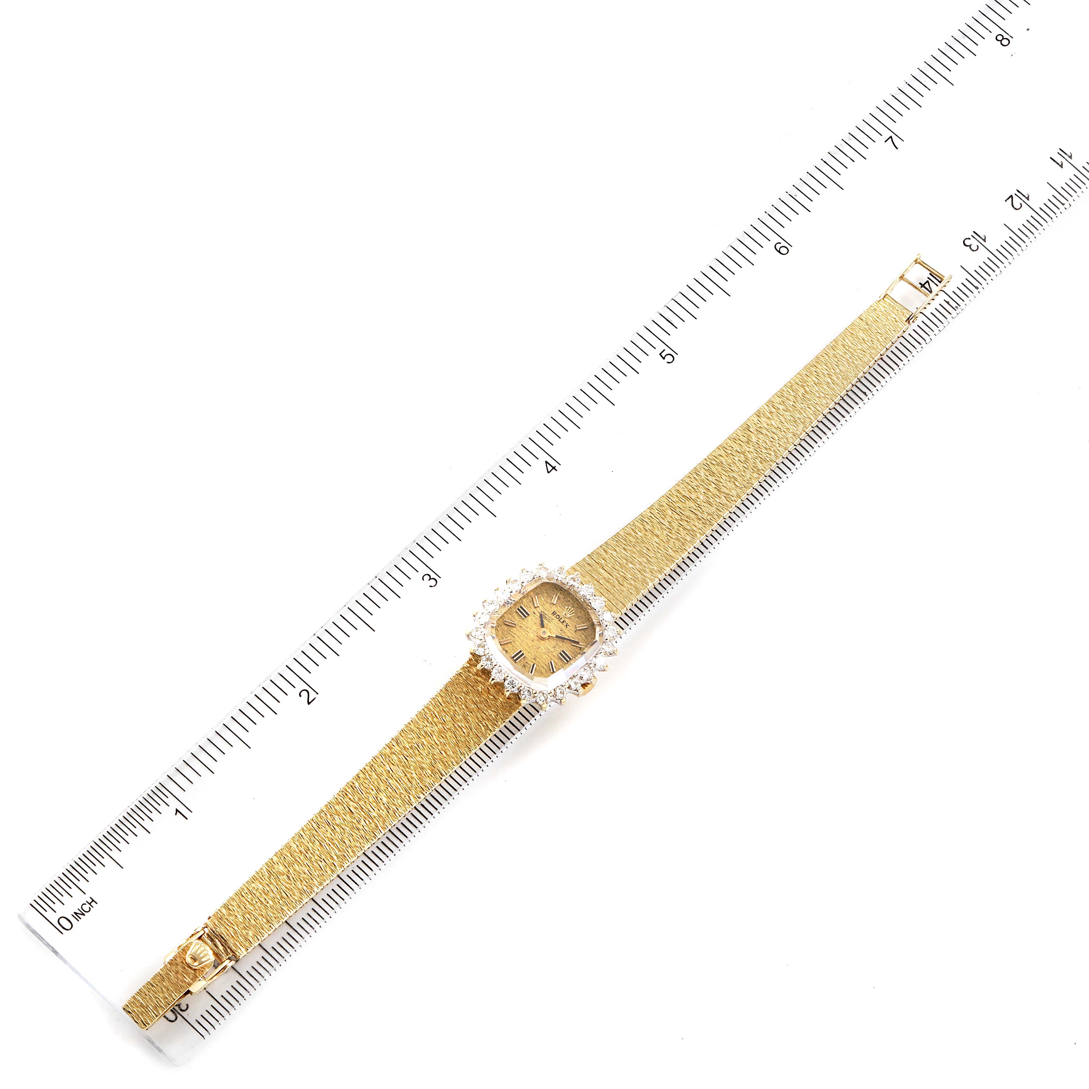 The image shows an overhead view of a Rolex Cocktail Women
s Yellow Gold Champagne Dial Women
s Yellow Gold Champagne Dial model watch, including its full strap and face, with a ruler for scale.