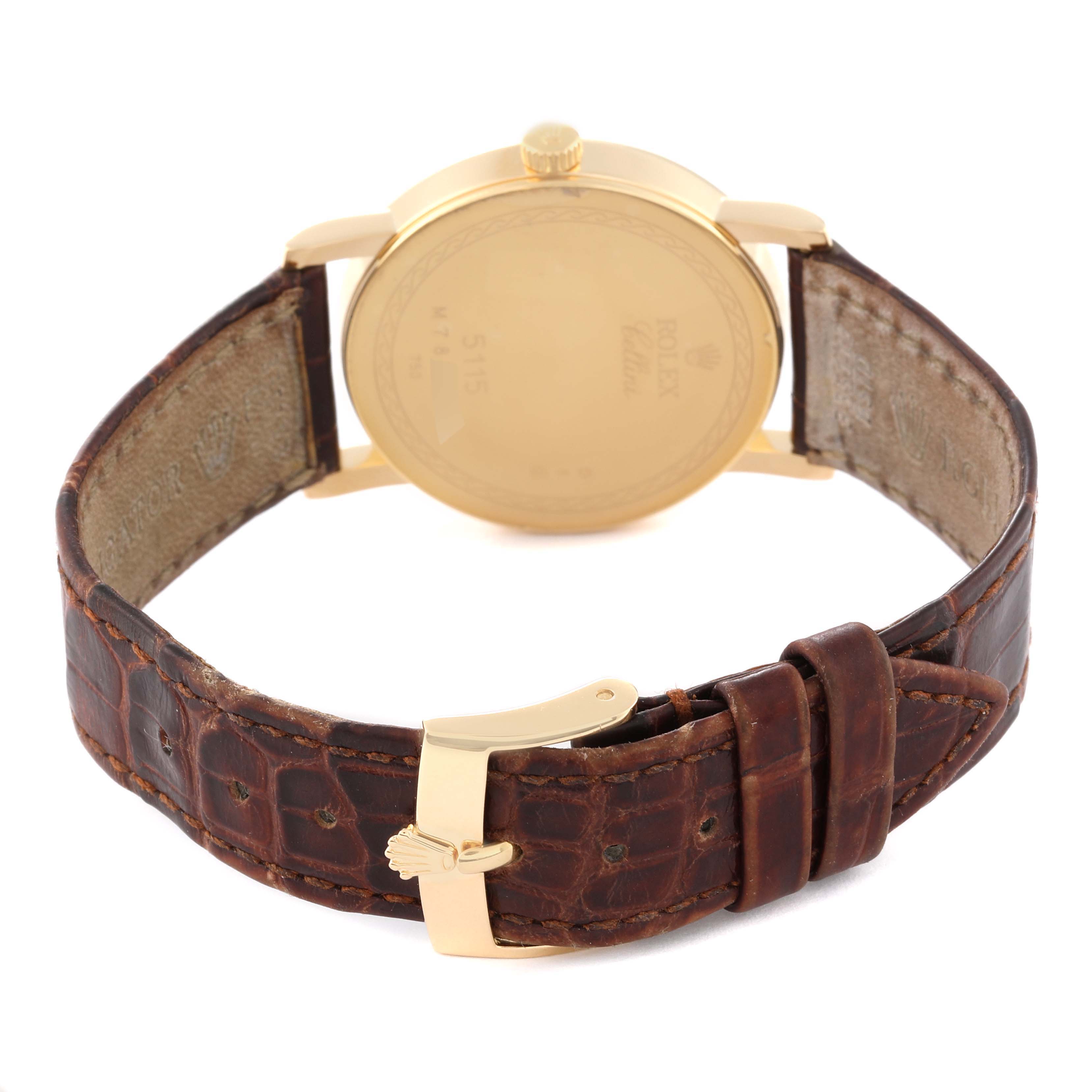 This is a rear view of a Rolex Cellini 5115 Men's Yellow Gold Silver Dial 5115 Men's Yellow Gold Silver Dial watch showing its gold case back and brown leather strap with a gold clasp.