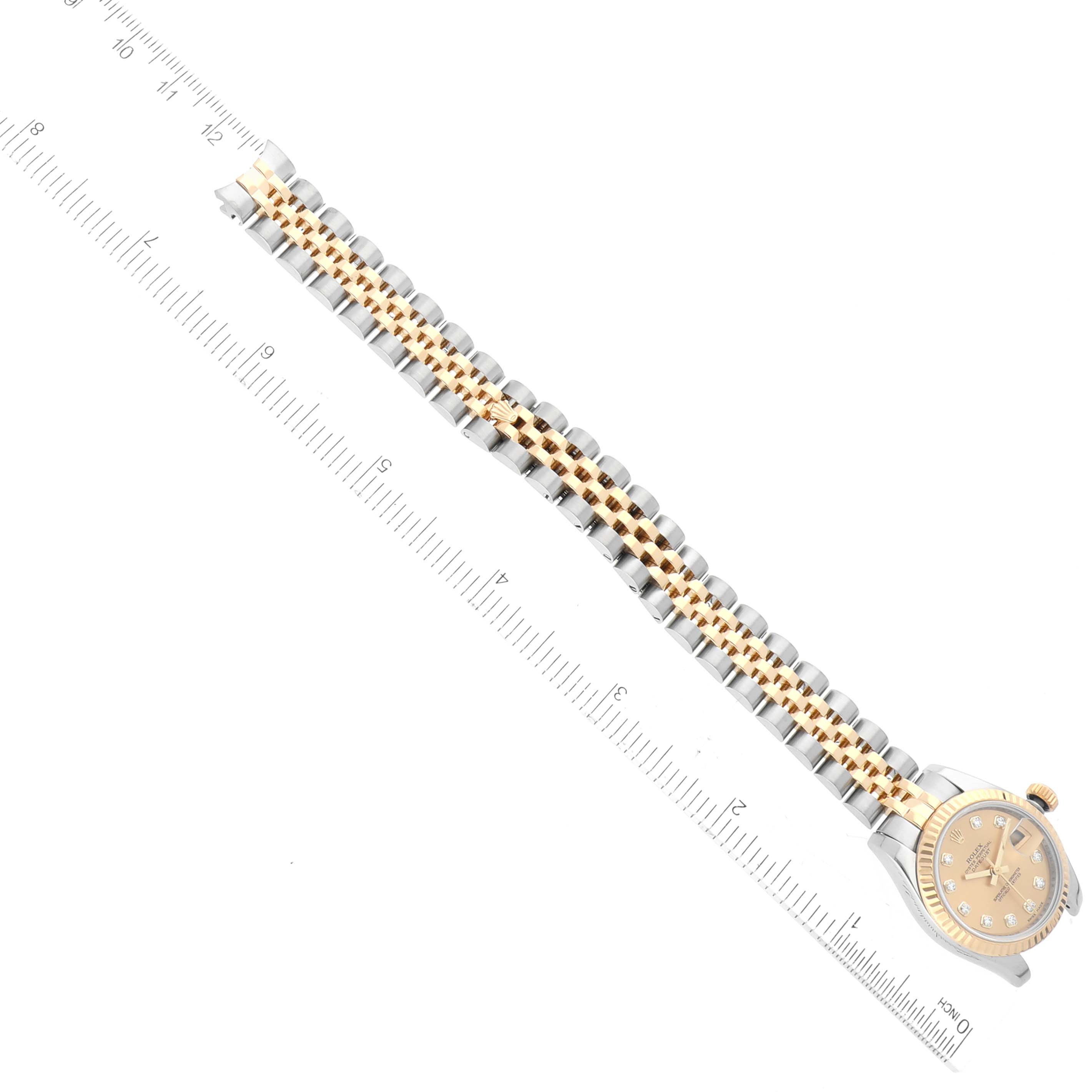 The image shows a Rolex Datejust 179173 Women's Steel and Gold (two tone) Champagne Dial 179173 Women's Steel and Gold (two tone) Champagne Dial with a gold and silver jubilee bracelet positioned alongside a ruler for scale.