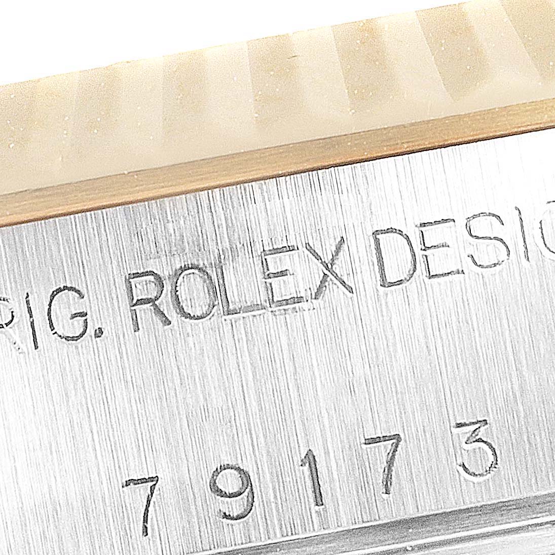 The image shows a close-up of the serial number and the engraving "ORIG. ROLEX DESIGN" on a Rolex Datejust 79173 Women's Steel and Gold (two tone) Champagne Dial 79173 Women's Steel and Gold (two tone) Champagne Dial watch case.