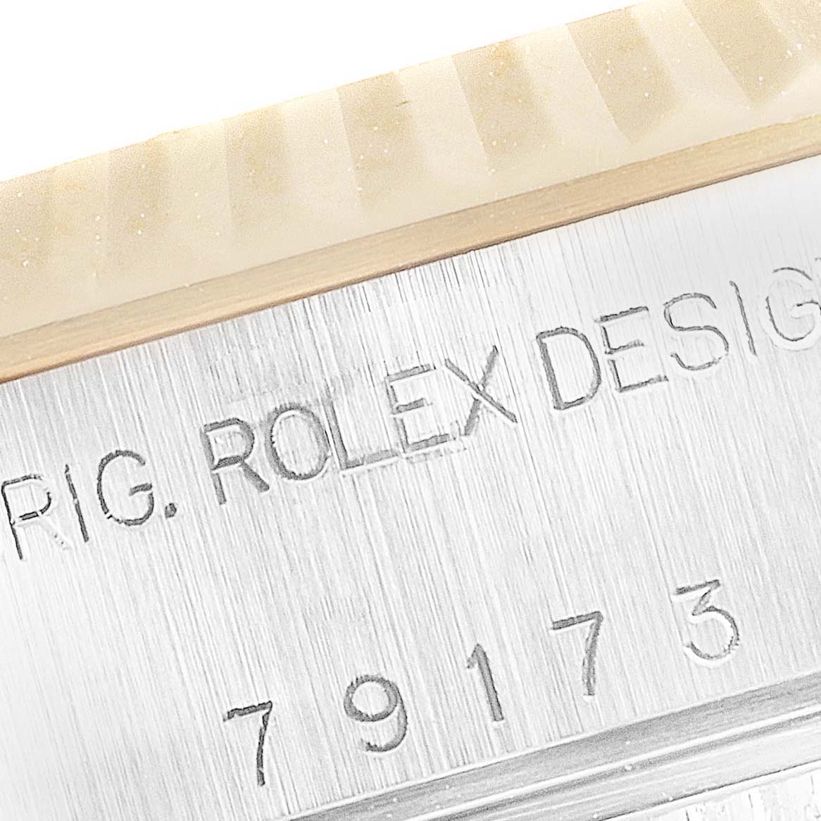 The image shows a close-up of the casing and serial number of a Rolex Datejust 79173 Women's Steel and Gold (two tone) Champagne Dial 79173 Women's Steel and Gold (two tone) Champagne Dial watch with part of the fluted bezel.