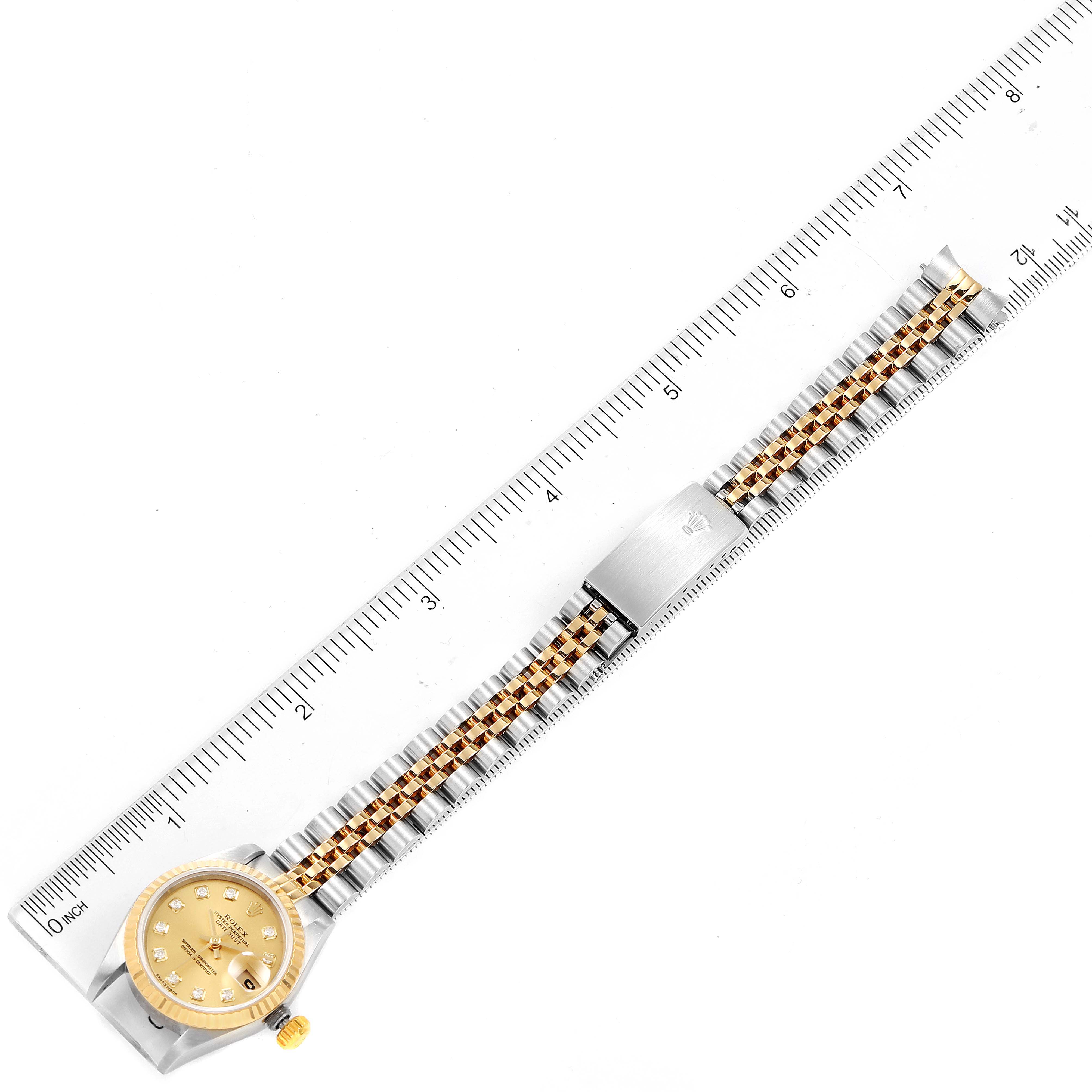 The Rolex Datejust 79173 Women's Steel and Gold (two tone) Champagne Dial 79173 Women's Steel and Gold (two tone) Champagne Dial watch is shown from the top view, includes the face, band, and clasp, alongside a ruler for scale.