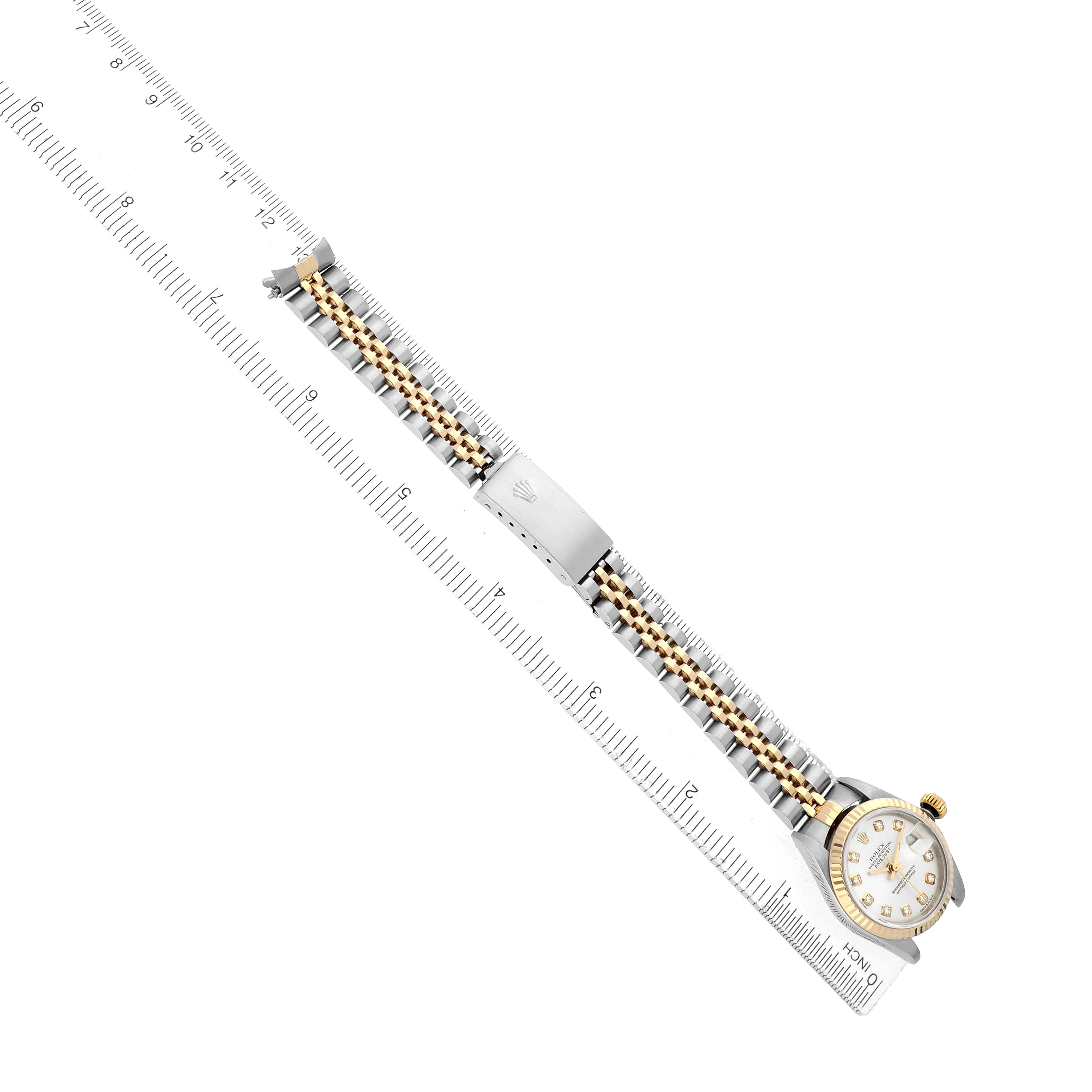 The Rolex Datejust 79173 Women
s Steel and Gold (two tone) Silver Dial watch is shown from a top-down angle, displaying the band and face, alongside a ruler for scale.