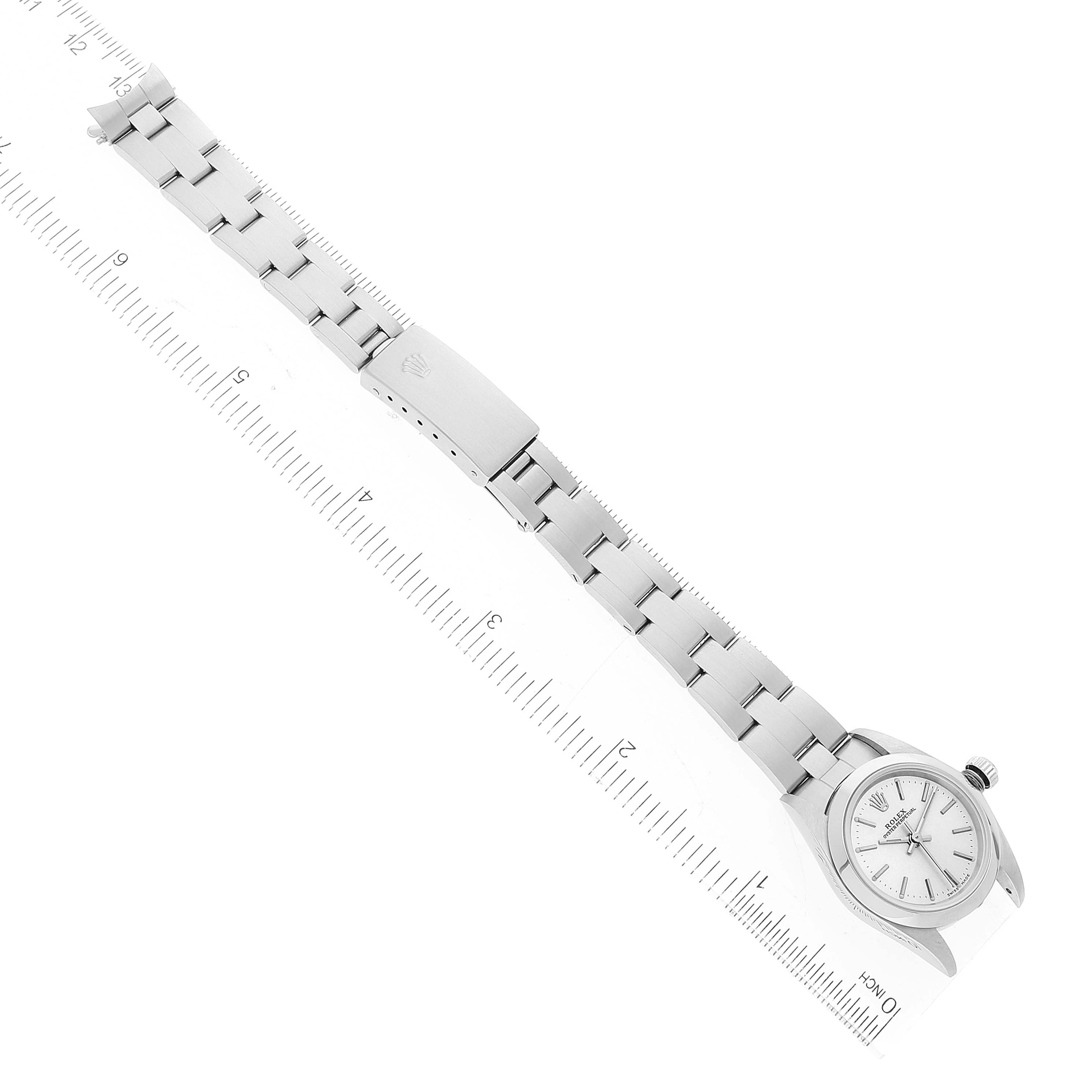 The image shows the Rolex Oyster Perpetual 76080 Women
s Stainless Steel Silver Dial 76080 Women
s Stainless Steel Silver Dial watch laid flat with its bracelet fully extended next to a ruler.