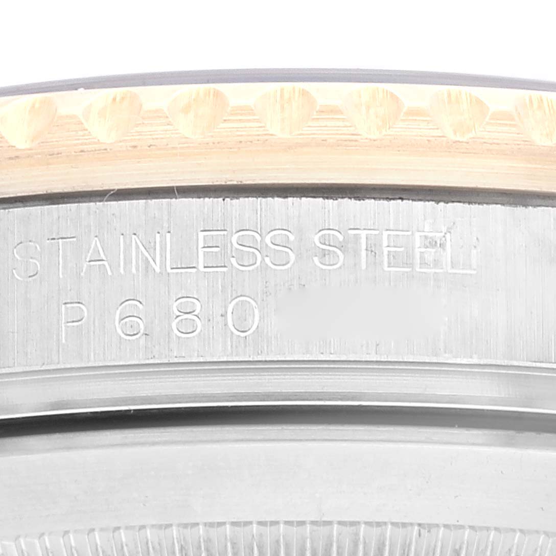 An extreme close-up of a Rolex Submariner 16613 Men's Steel and Gold (two tone) Black Dial 16613 Men's Steel and Gold (two tone) Black Dial watch, showing part of the bezel and stainless steel case with engravings.