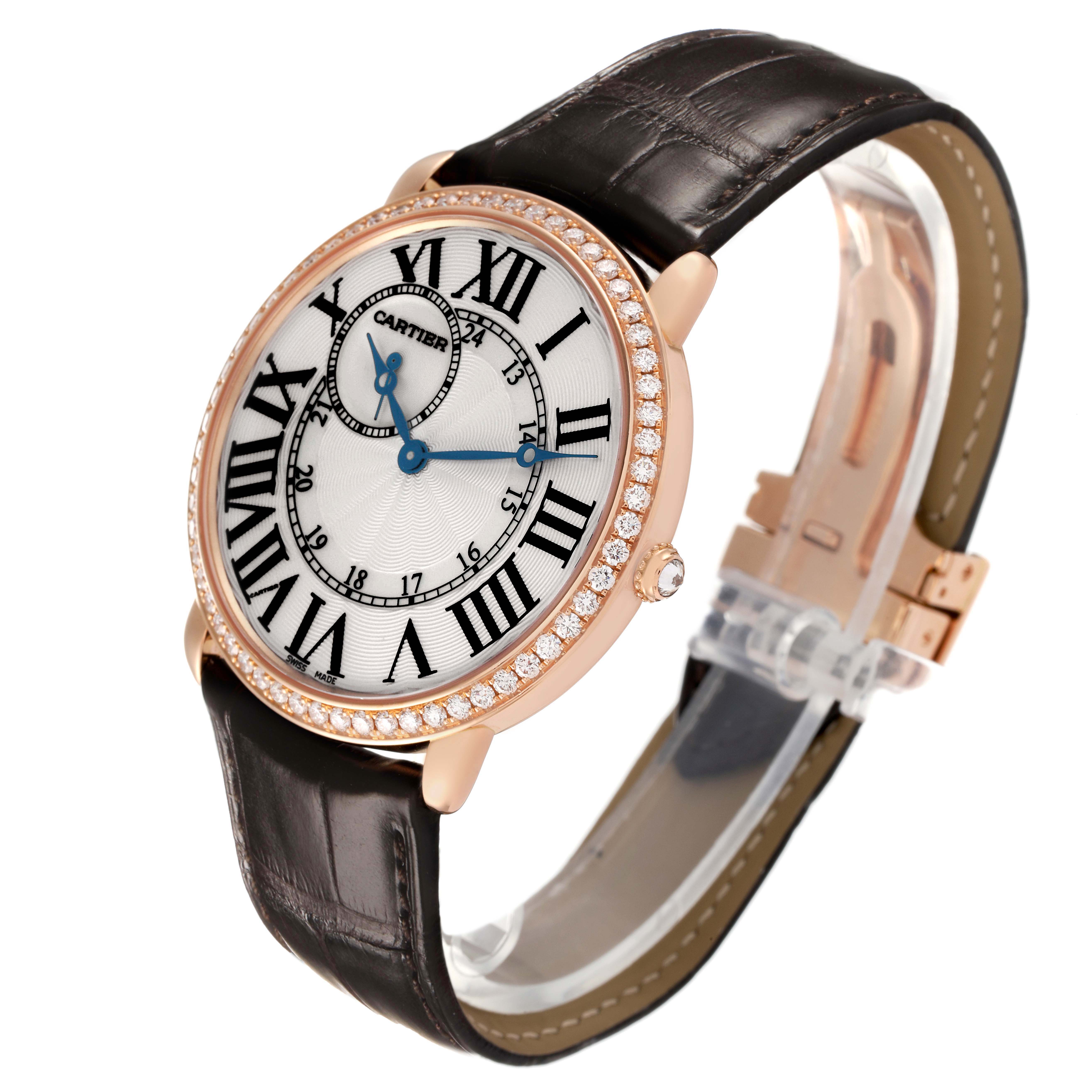 The Cartier Ronde WR007001 Men's Rose Gold Silver Dial watch is shown at a three-quarter angle, highlighting its face, Roman numerals, blue hands, diamond bezel, and leather strap.