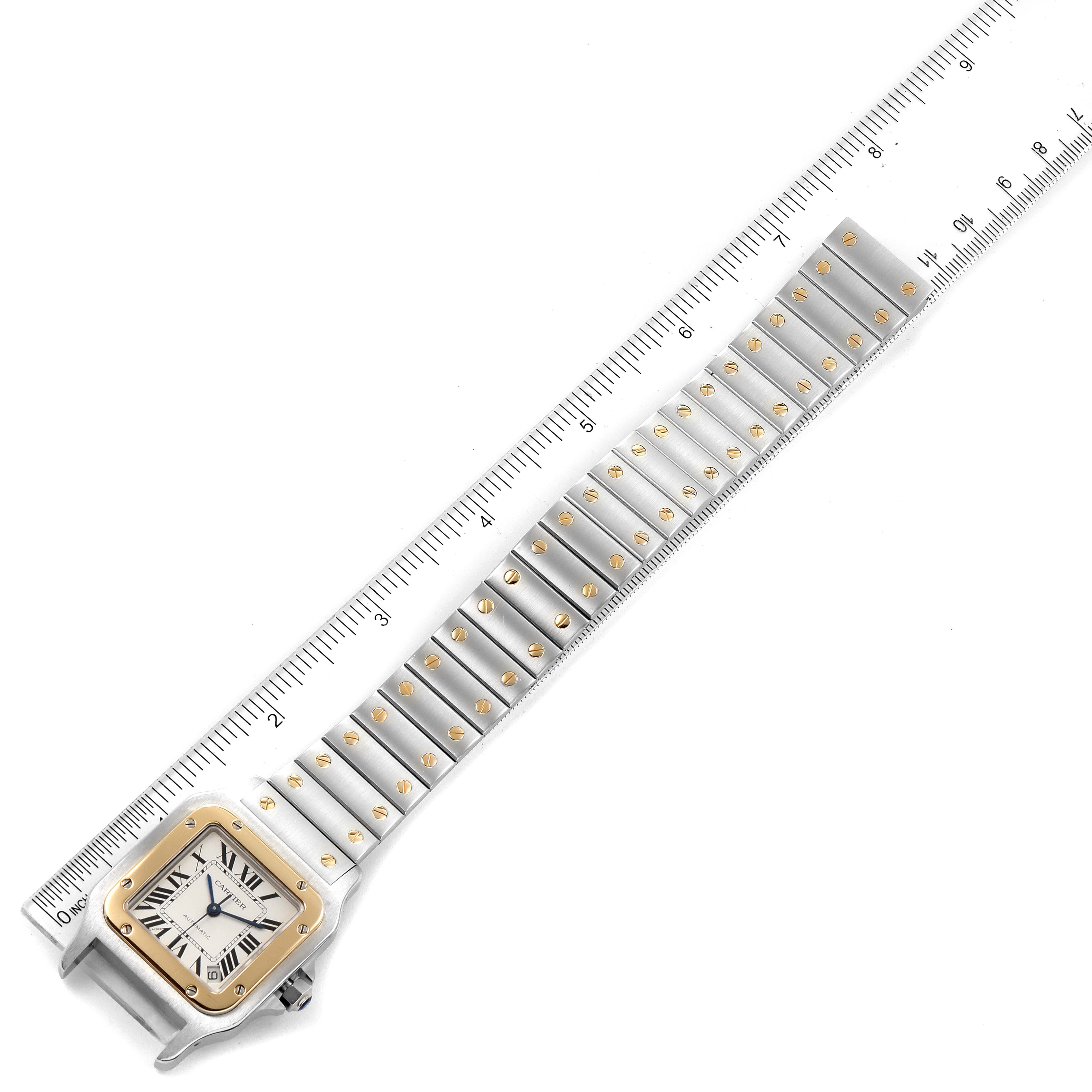 The image shows a Santos model by Cartier from a top-down angle, highlighting its watch face and metal strap with a ruler for scale.