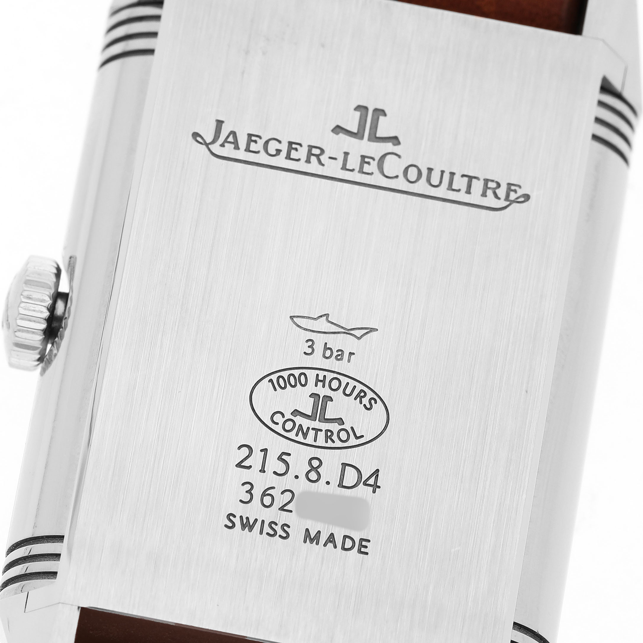 The image shows the back of a Jaeger-LeCoultre Reverso watch featuring engravings and the crown.