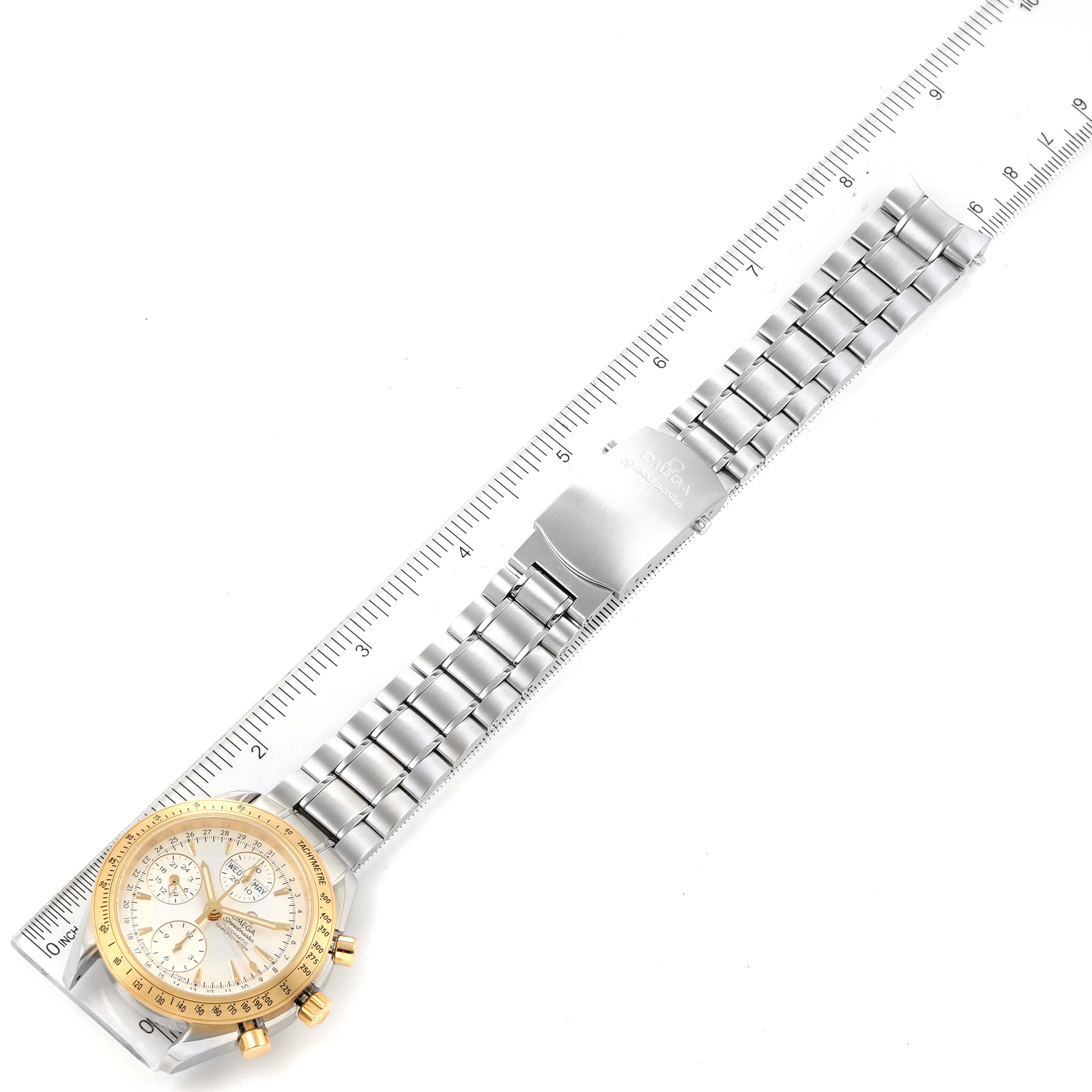 The image shows an Omega Speedmaster 323.21.40.44.02.001 Men's Steel and Gold (two tone) Silver Dial 323.21.40.44.02.001 Men's Steel and Gold (two tone) Silver Dial watch laying flat with a metal bracelet next to a ruler for measurement.