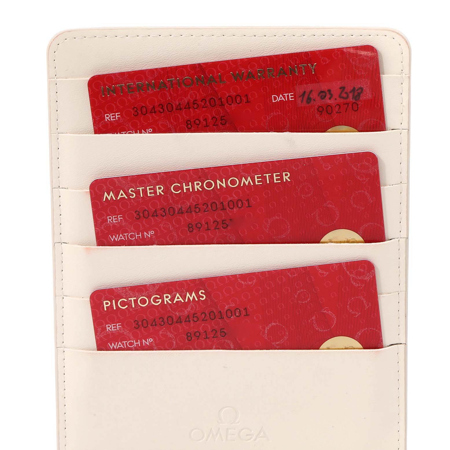 This image shows three red warranty cards in a white Omega holder for the Speedmaster model.