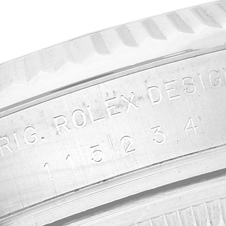 The image shows a close-up angle of the model and serial number engraving on the side of a Rolex Date 115234 Men's Stainless Steel White Dial 115234 Men's Stainless Steel White Dial watch case.