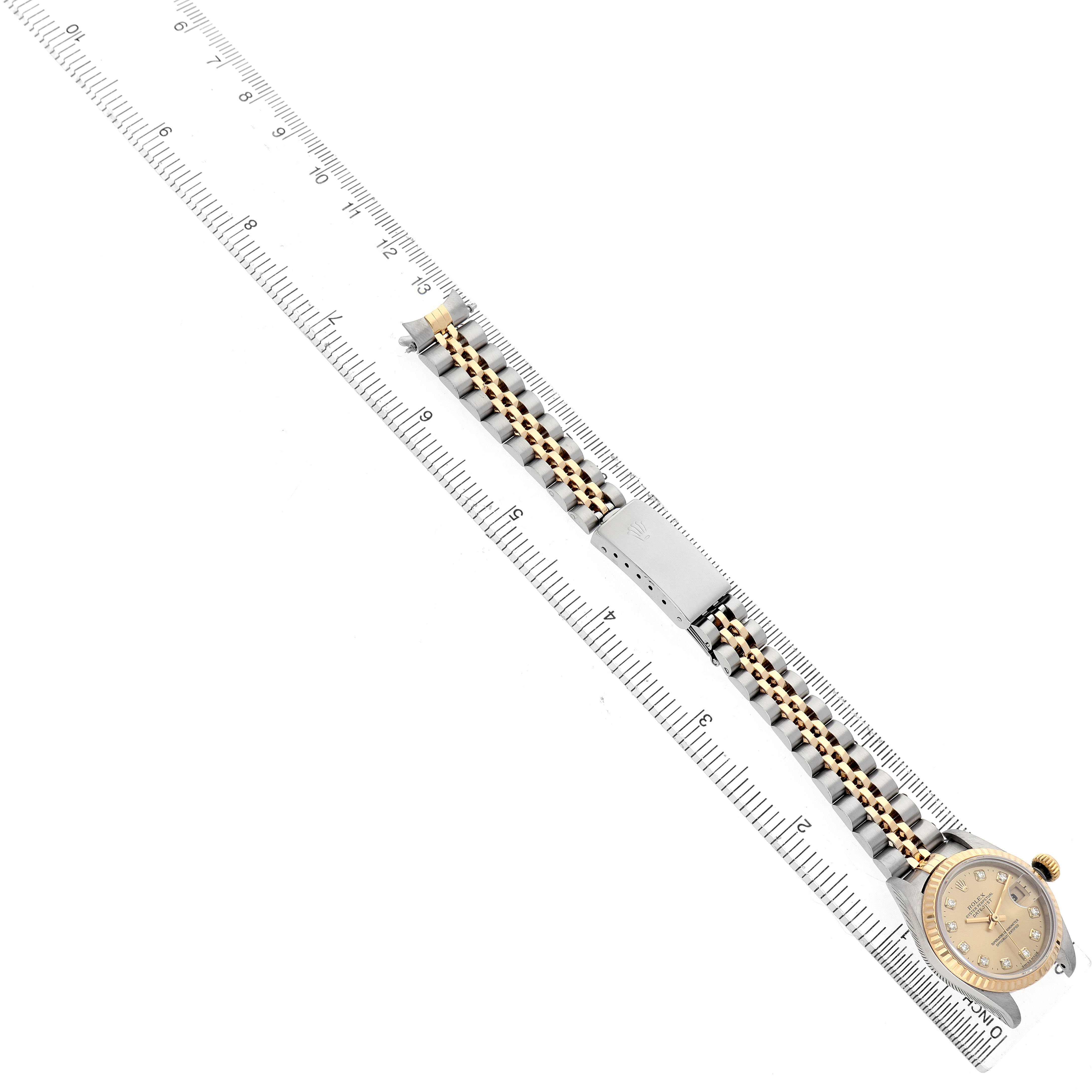 The Rolex Datejust 69173 Women's Steel and Gold (two tone) Champagne Dial watch is shown angled diagonally with the bracelet fully extended alongside a ruler.