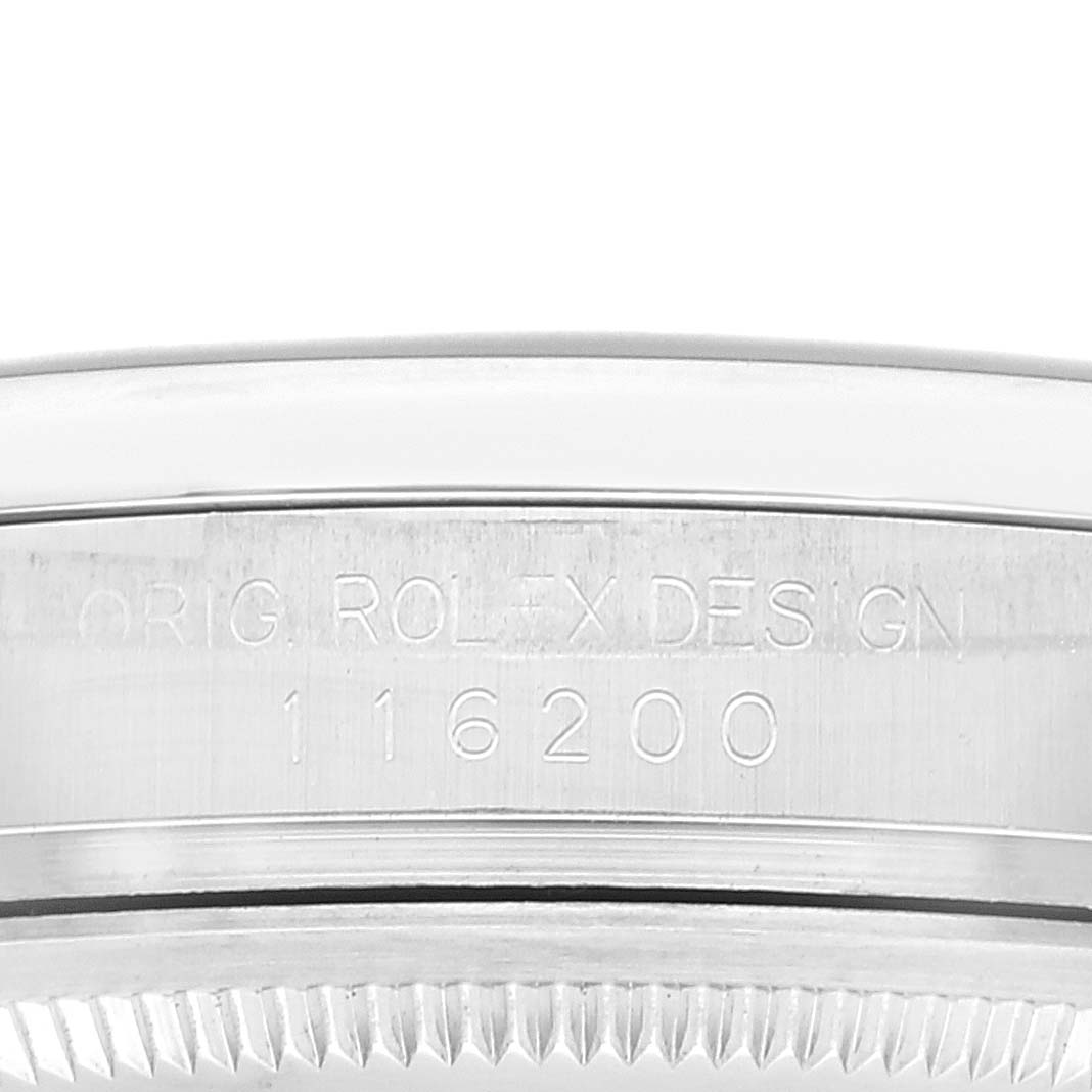 The image shows a close-up side view of the case, serial number, and part of the fluted bezel of a Rolex Datejust 116200 Men's Stainless Steel Blue Dial 116200 Men's Stainless Steel Blue Dial model.