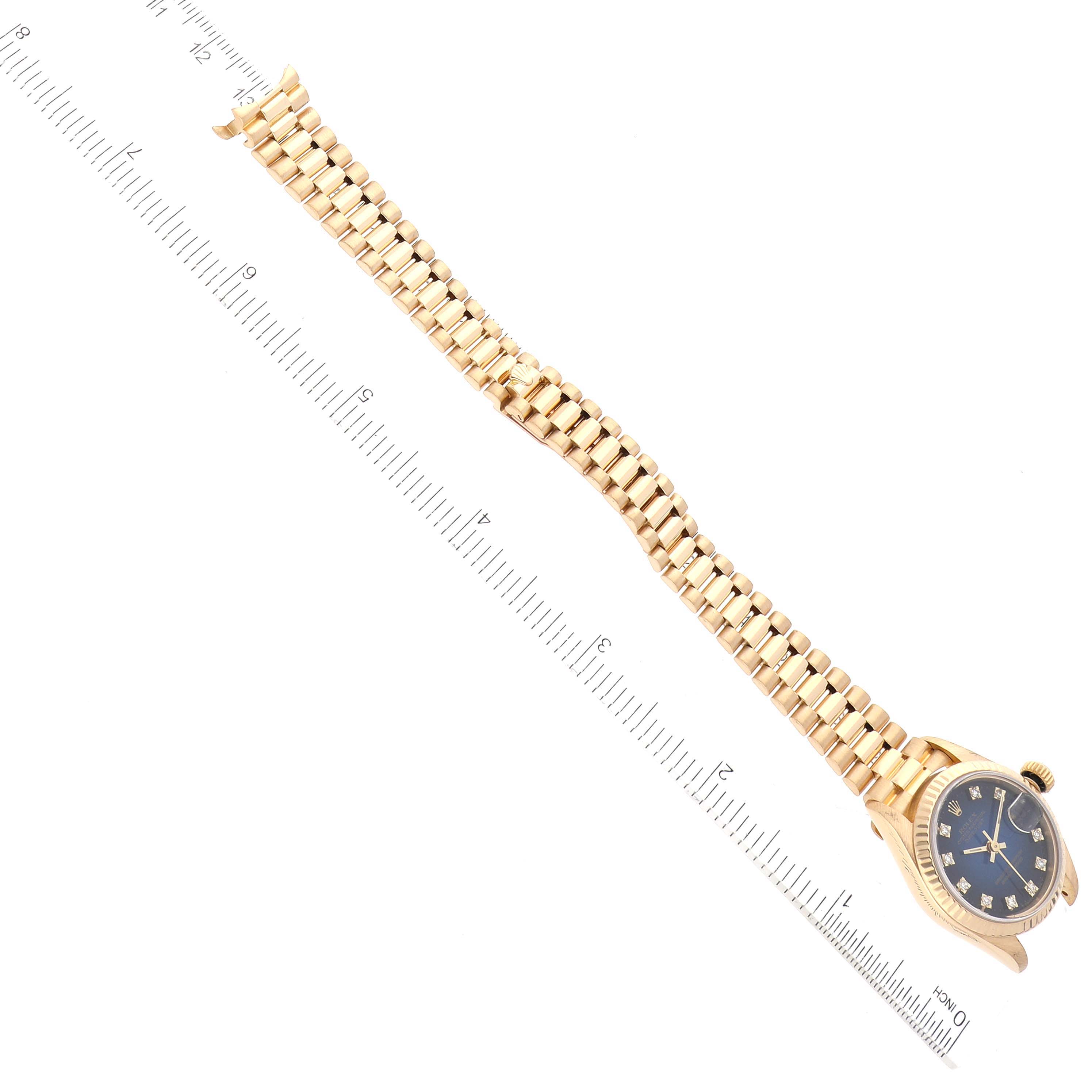 The image shows a Rolex President 69178 Women's Yellow Gold Blue Dial 69178 Women's Yellow Gold Blue Dial model watch at an overhead angle, displaying the face, case, and full bracelet against a ruler.