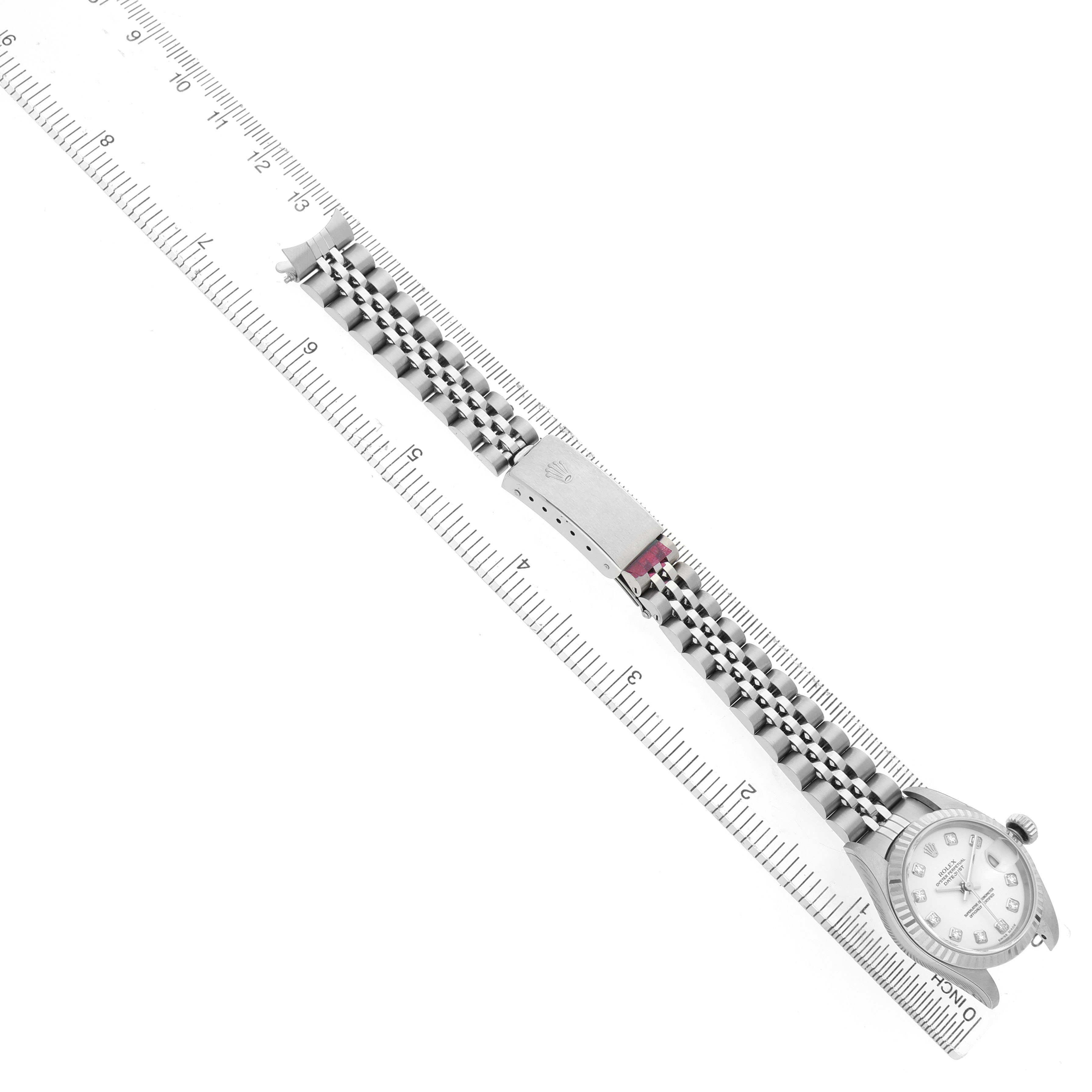 The image shows a Rolex Datejust 179174 Women's Stainless Steel White Dial watch laid flat, displaying the bracelet and clasp alongside a ruler for scale.