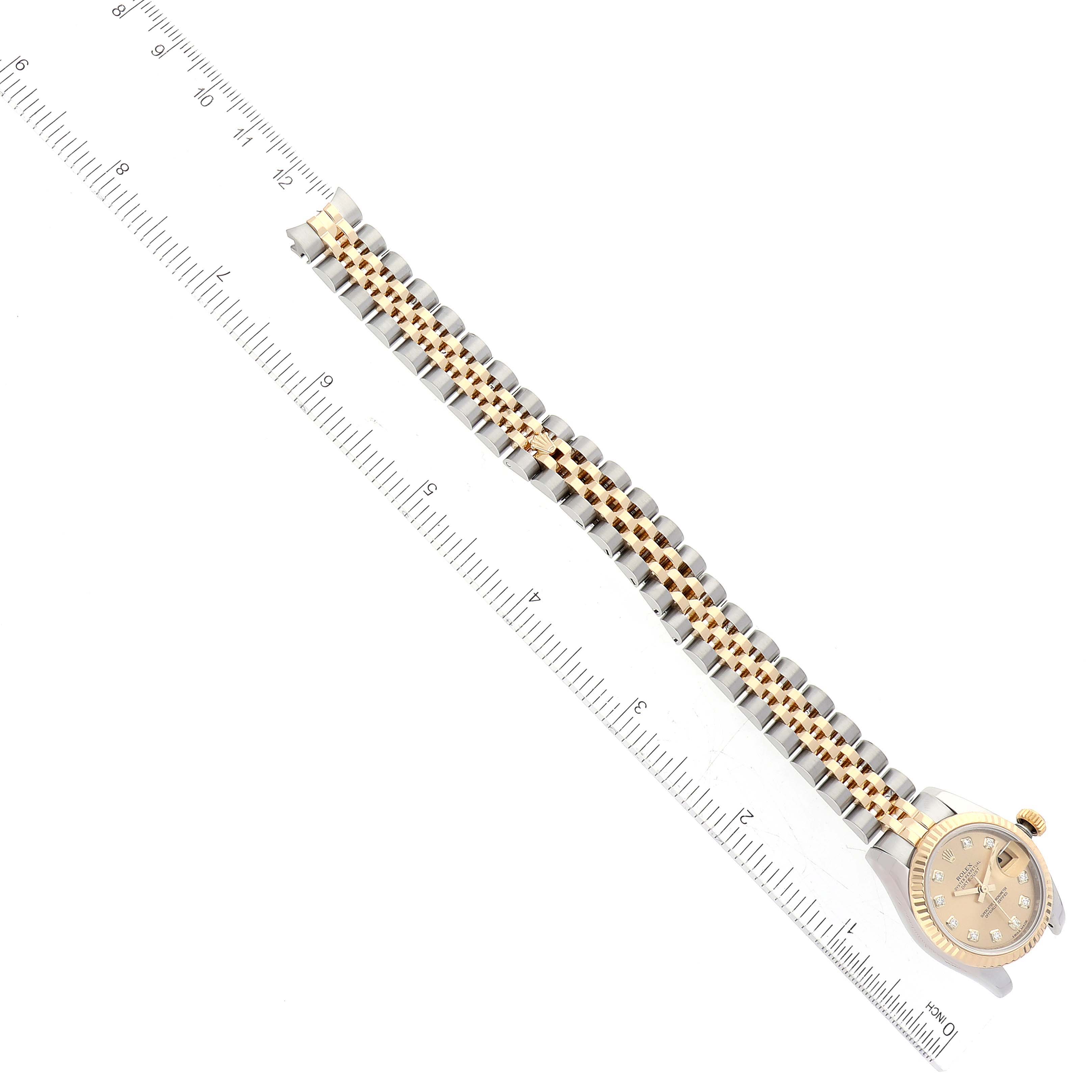 The image shows a Rolex Datejust 179173 Women's Steel and Gold (two tone) Champagne Dial 179173 Women's Steel and Gold (two tone) Champagne Dial watch with the bracelet extended, lying next to a ruler for scale.