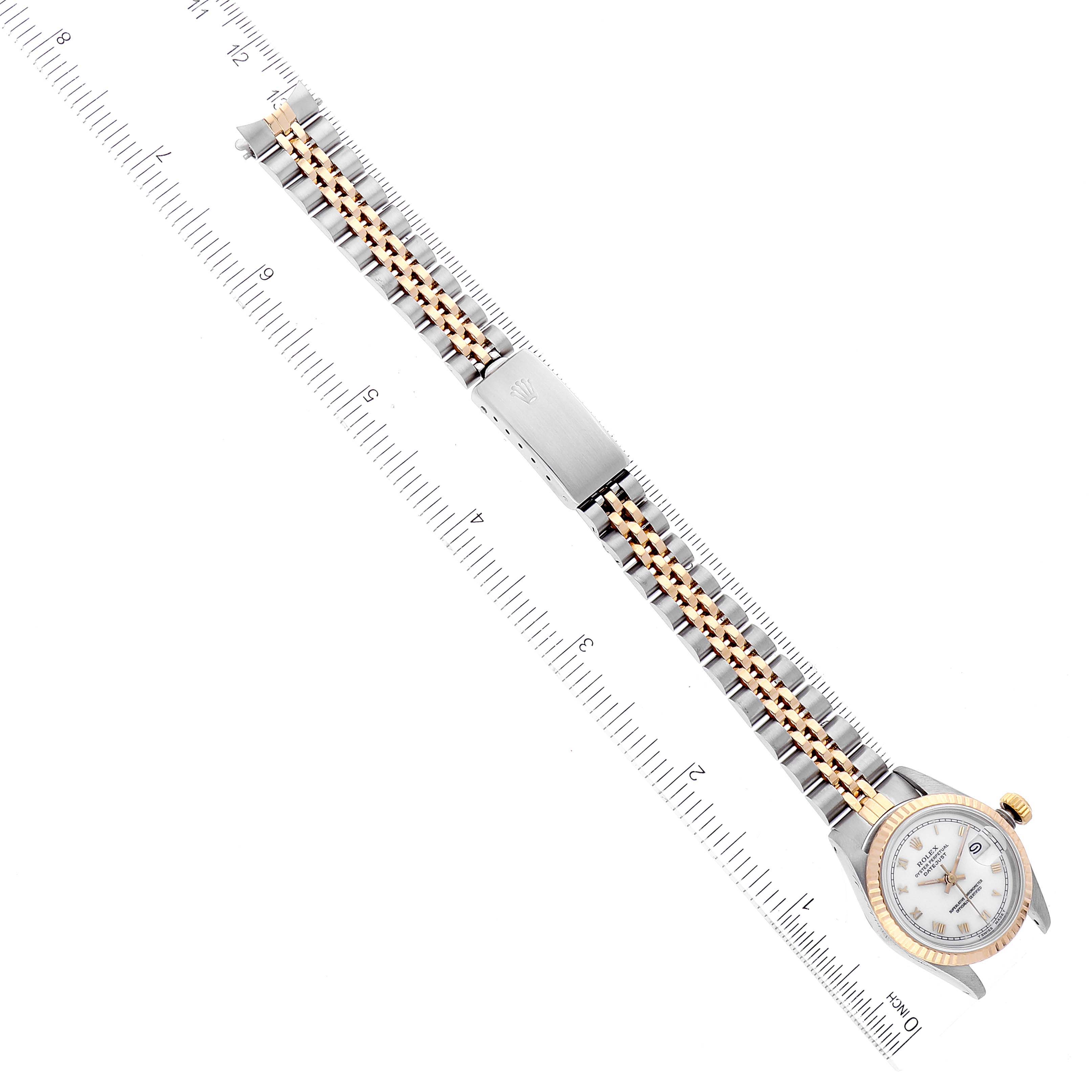 The image shows a top-down view of a Rolex Datejust 69173 Women's Steel and Gold (two tone) White Dial 69173 Women's Steel and Gold (two tone) White Dial watch, highlighting its face, bezel, and bi-color metal bracelet with a ruler for size reference.