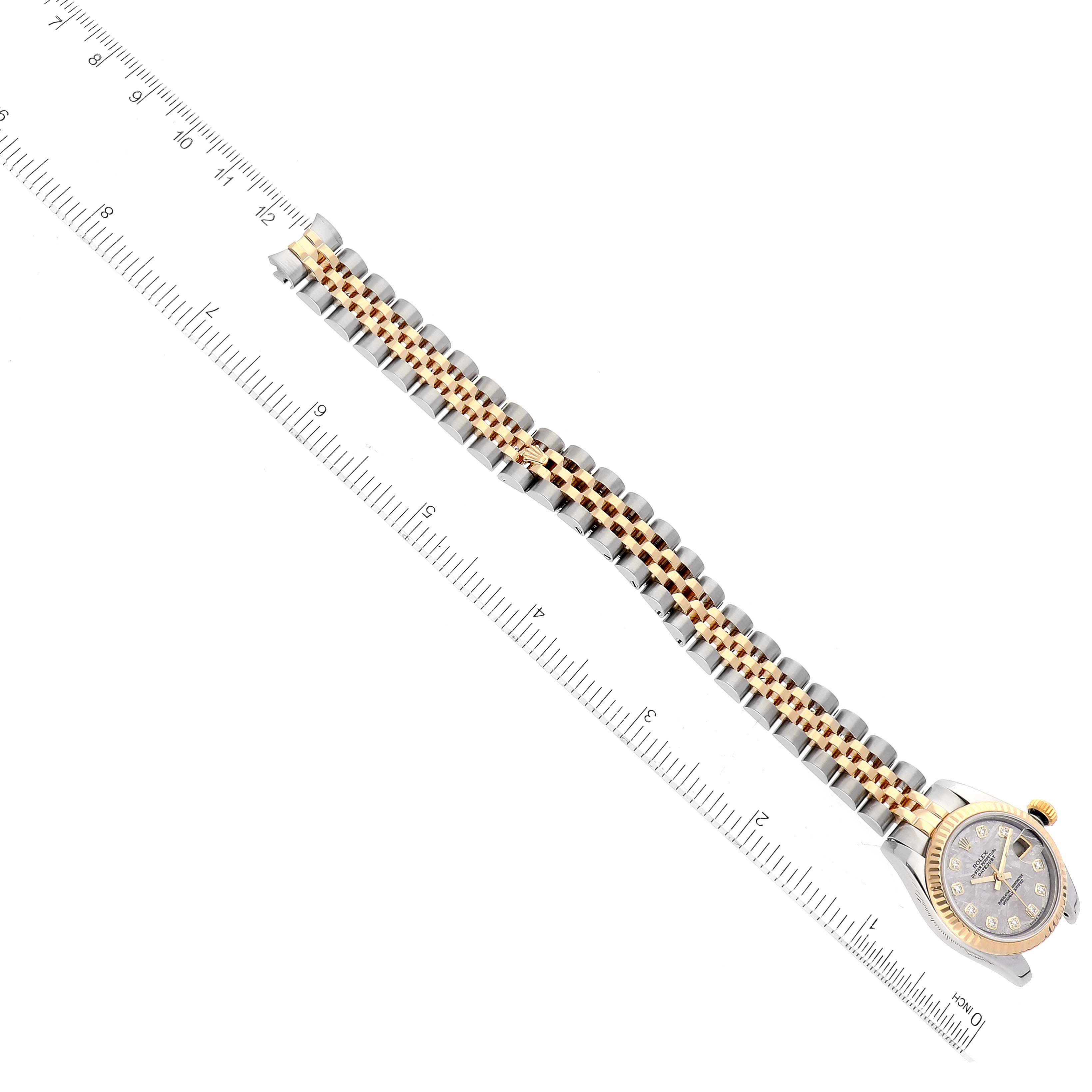 The image shows a top view of a Rolex Datejust 179173 Women's Steel and Gold (two tone) Silver Dial 179173 Women's Steel and Gold (two tone) Silver Dial watch with a two-tone bracelet and a ruler for scale.