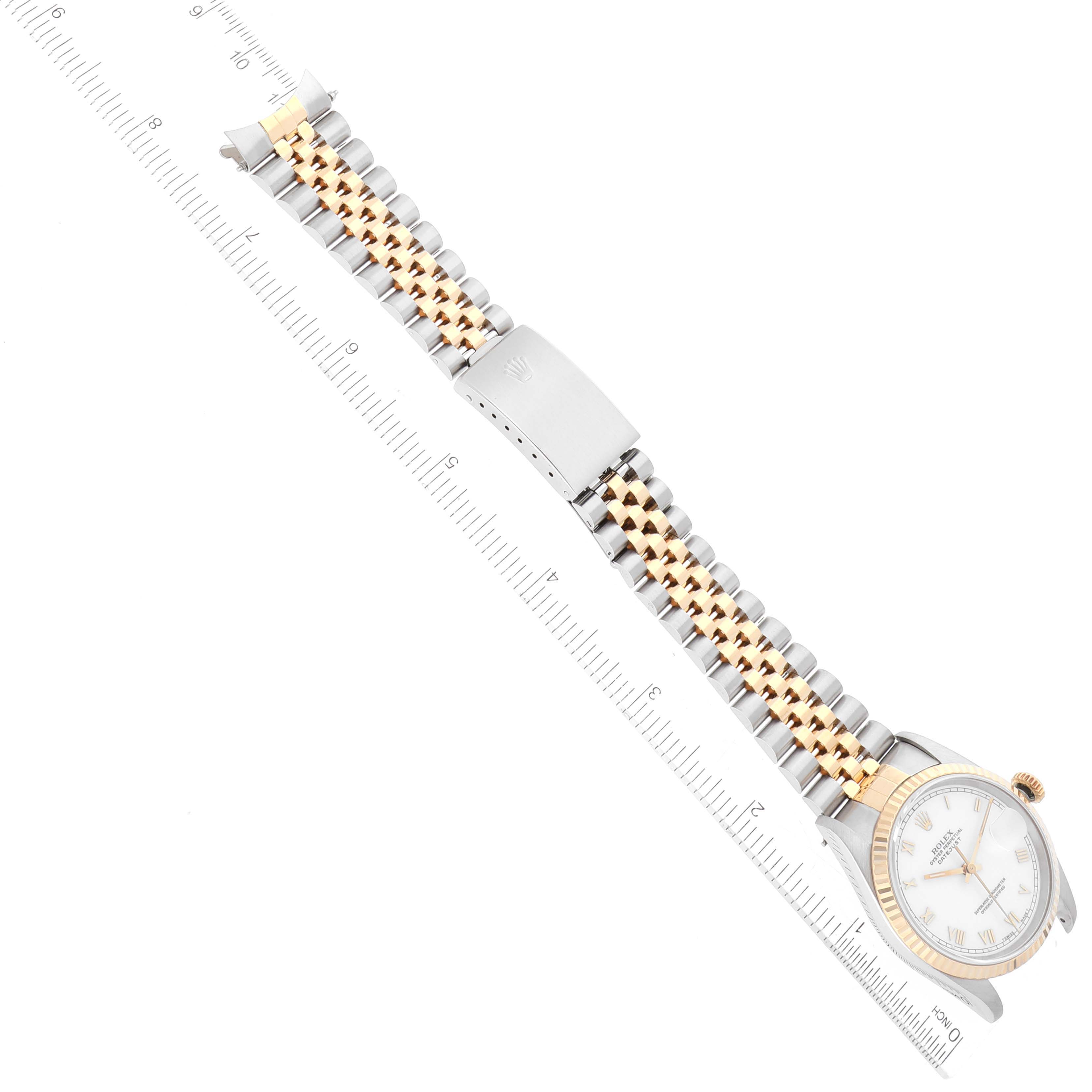 The Rolex Datejust 16233 Men's Steel and Gold (two tone) White Dial 16233 Men's Steel and Gold (two tone) White Dial watch is shown from above, displaying its face, jubilee bracelet, and clasp alongside a ruler for scale.