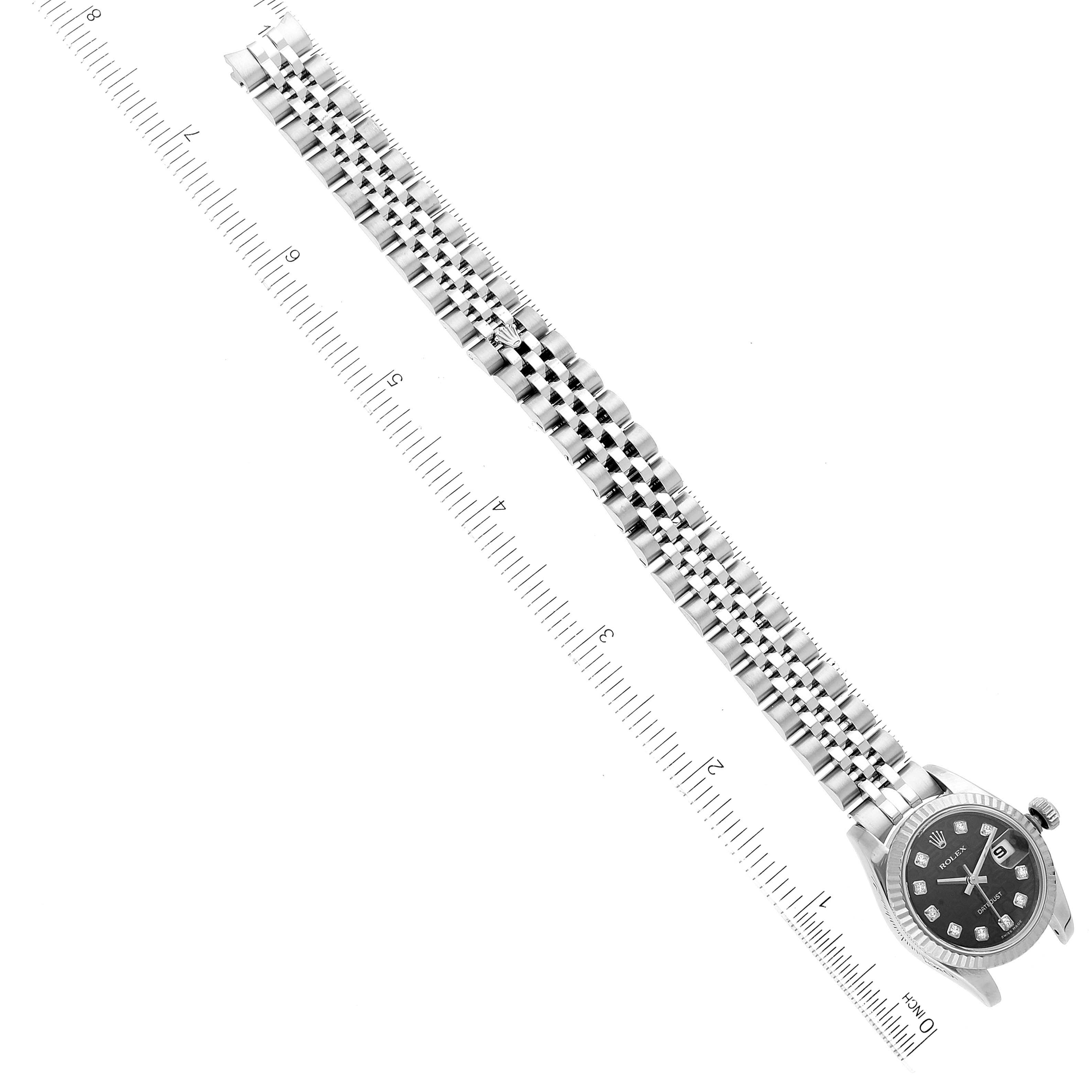 The image shows a Rolex Datejust 179174 Women's Stainless Steel Black Dial 179174 Women's Stainless Steel Black Dial watch laid flat next to a ruler, highlighting its bracelet and face from a top-down angle.