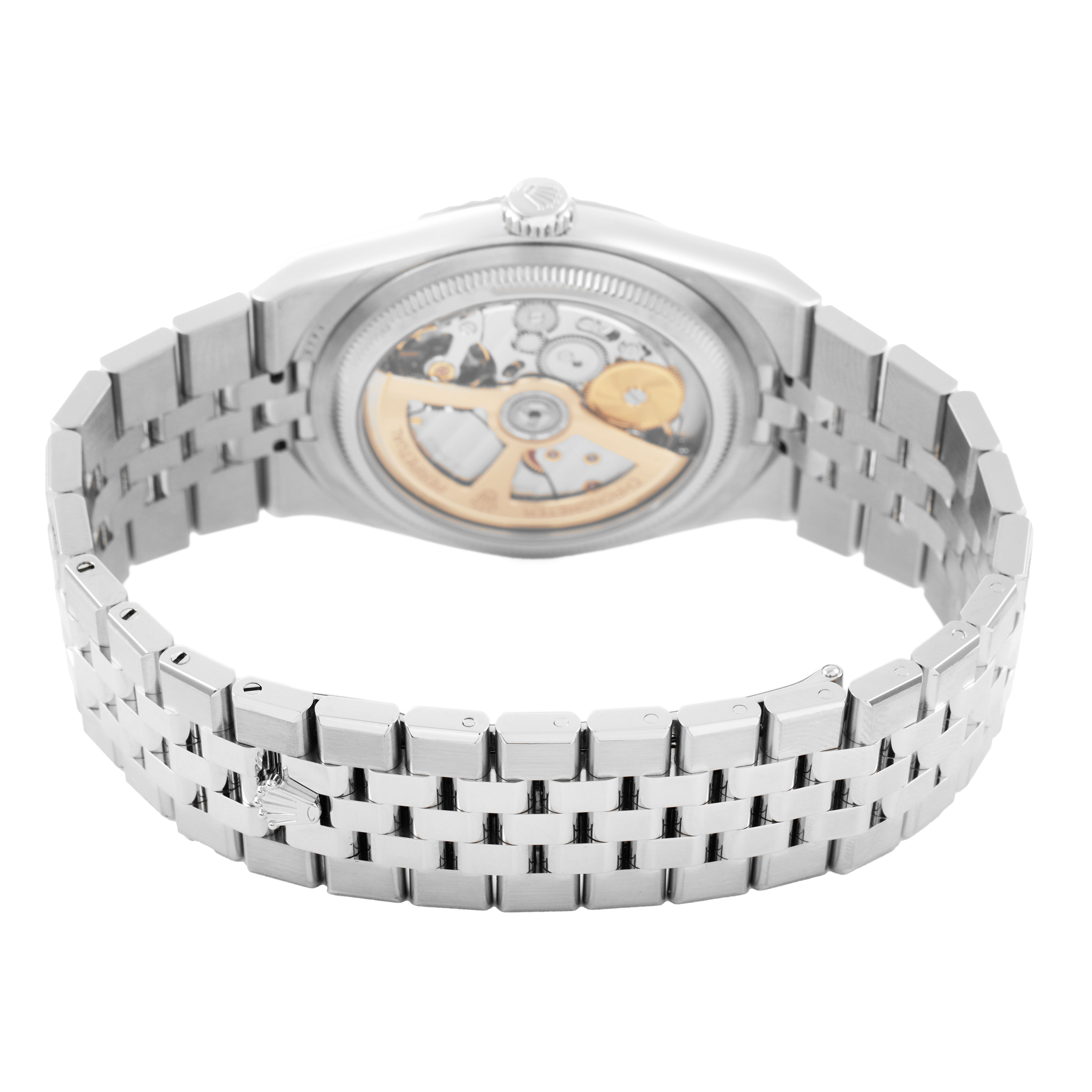 The image shows the back of a Rolex Land-Dweller watch, displaying its movement and metal bracelet.