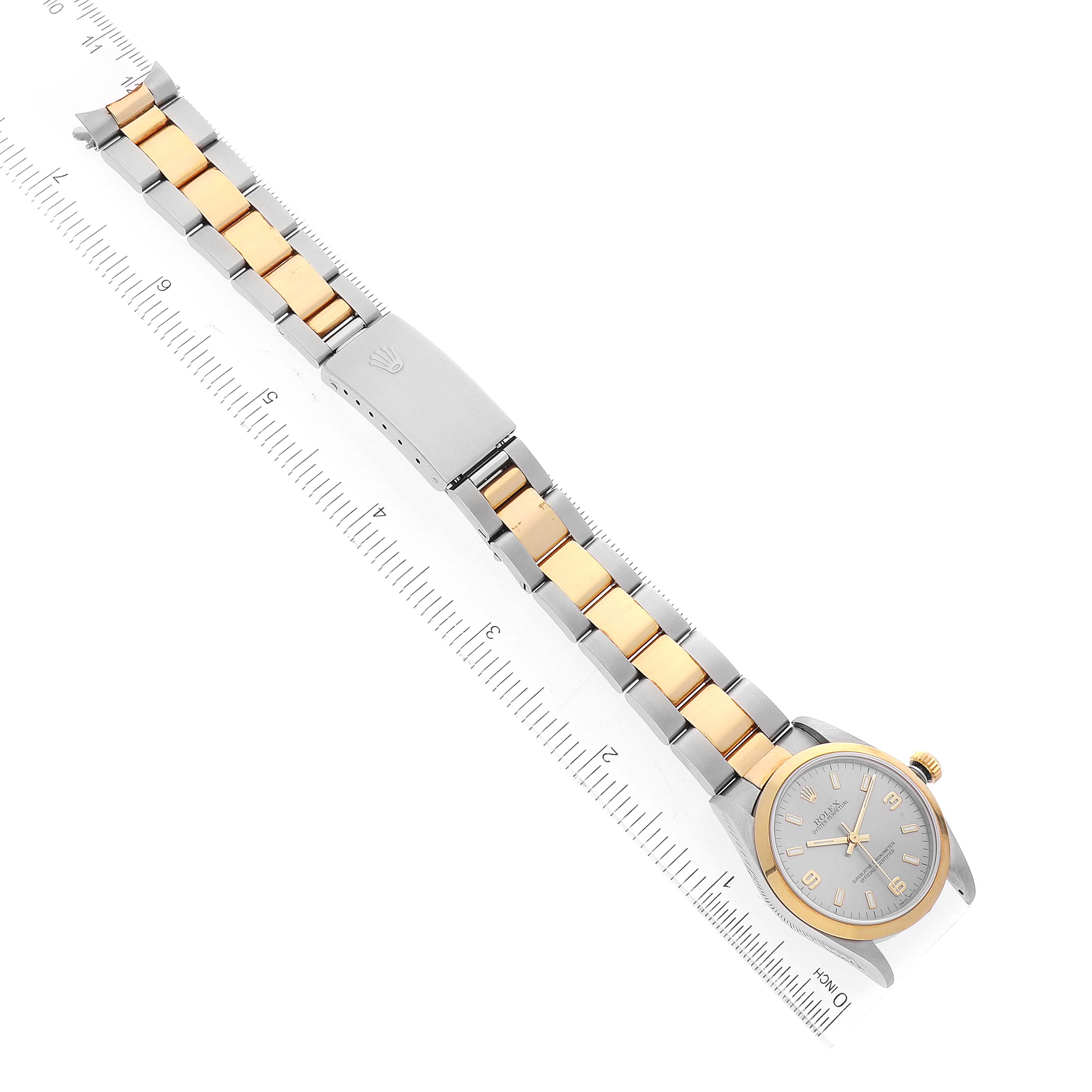 The image shows a top view of a Mid-Size Rolex watch
s entire length, including the face, case, bracelet, and clasp, next to a ruler.
