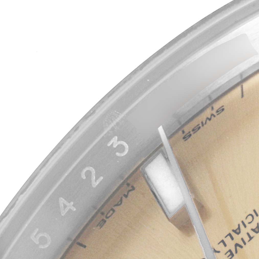 This close-up image shows the dial and partial hour markers of a Rolex Oyster Perpetual 114200 Men's Stainless Steel Champagne Dial 114200 Men's Stainless Steel Champagne Dial watch.