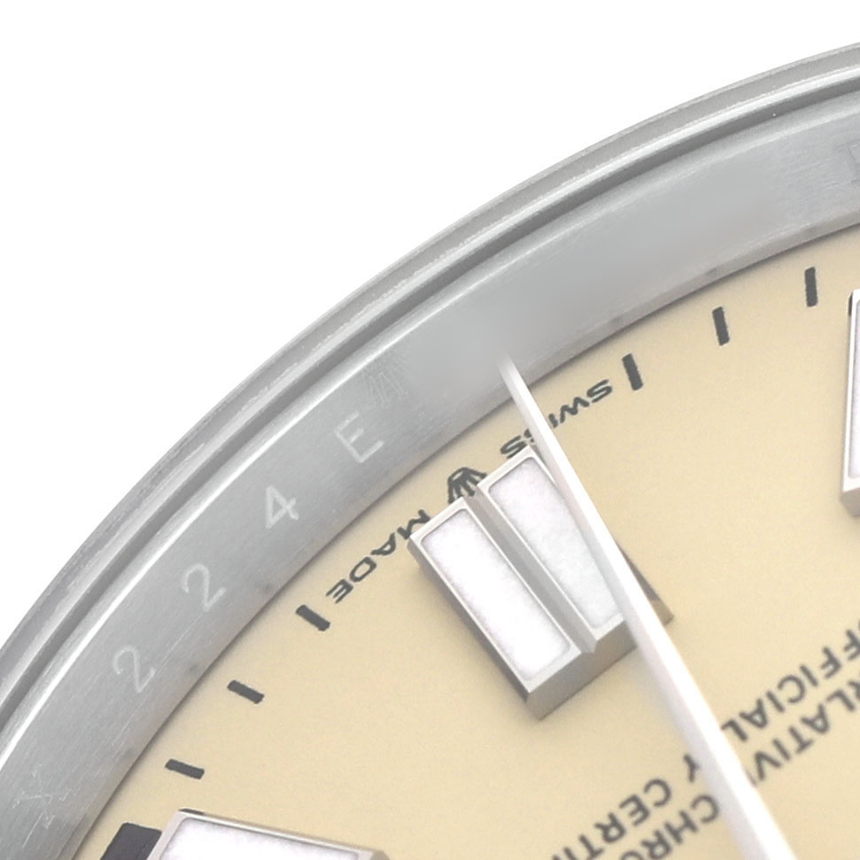 The image shows a close-up of the Rolex Oyster Perpetual 134300 Men's Stainless Steel Beige Dial watch face, highlighting the bezel, hour marker, and part of the dial.