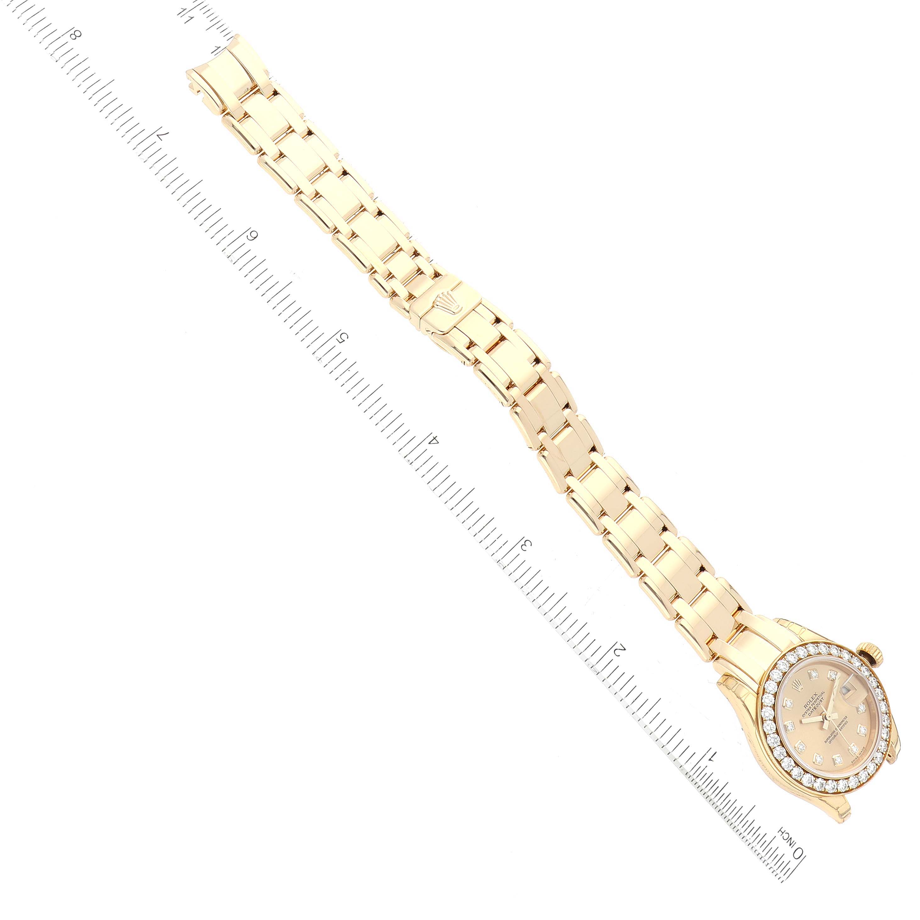 The image shows a Rolex Pearlmaster 80298 Women's Yellow Gold Champagne Dial 80298 Women's Yellow Gold Champagne Dial watch laid flat beside a ruler, displaying the watch's face and full bracelet.
