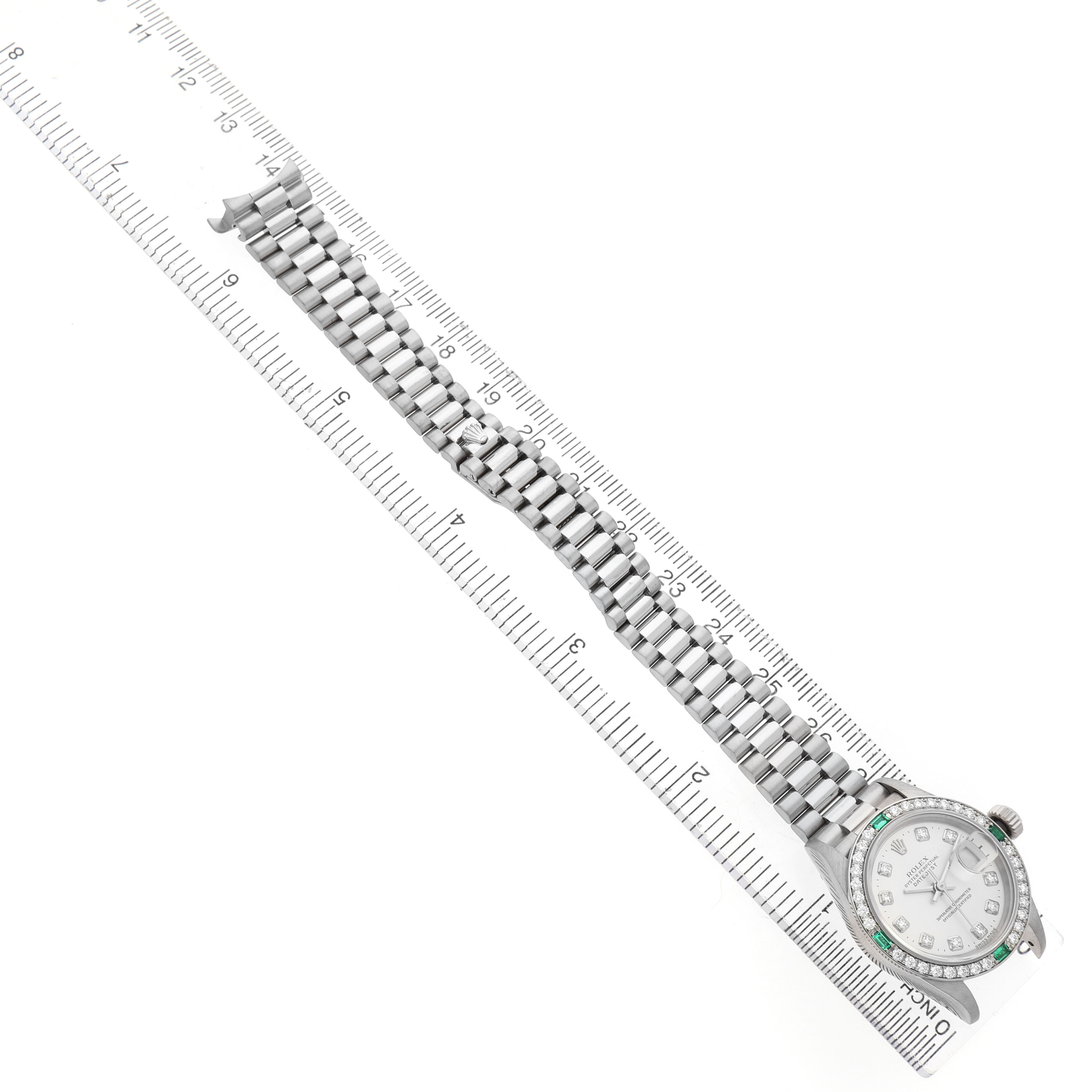 The Rolex President 79079 Women's White Gold Silver Dial model is shown from a top-down angle, highlighting the full bracelet and face on a ruler for scale.