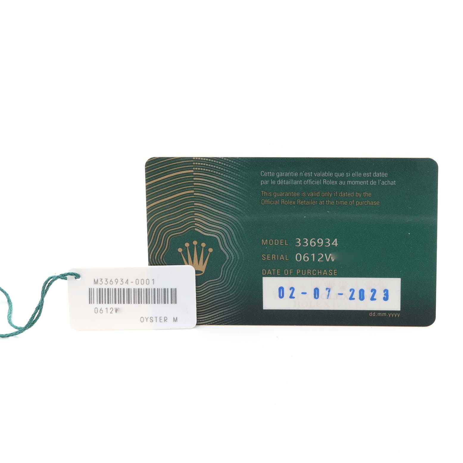 This image shows a Rolex Sky-Dweller 336934 Men
s Stainless Steel Green Dial 336934 Men
s Stainless Steel Green Dial model warranty card and a tag with a model number and serial number.