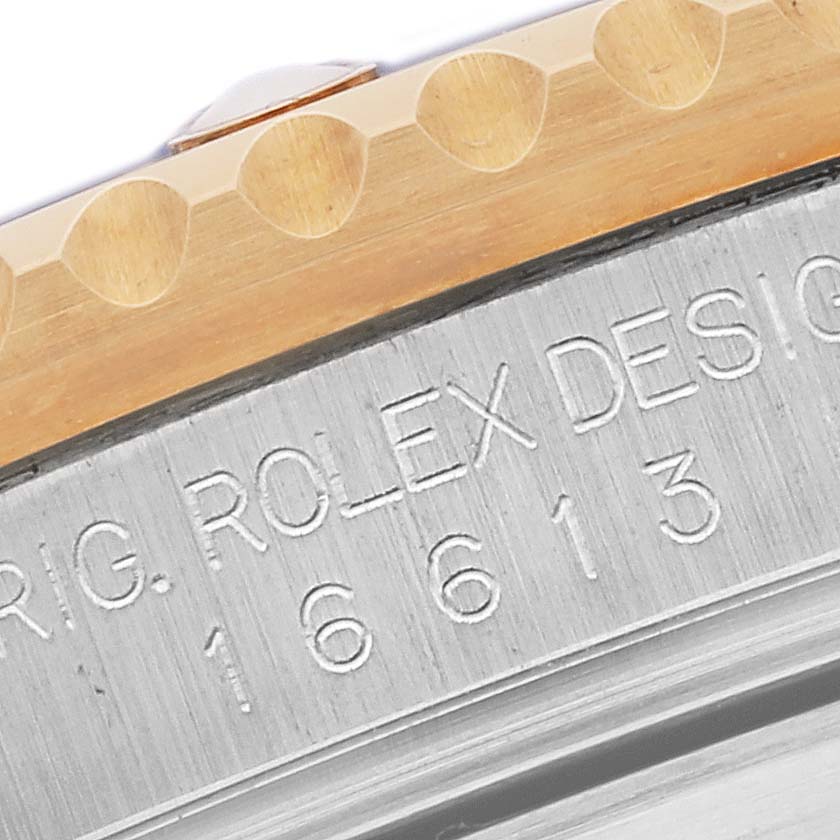 The image shows a close-up of the Rolex Submariner 16613 Men's Steel and Gold (two tone) Blue Dial 16613 Men's Steel and Gold (two tone) Blue Dial's engraved watch case and gold bezel edge.