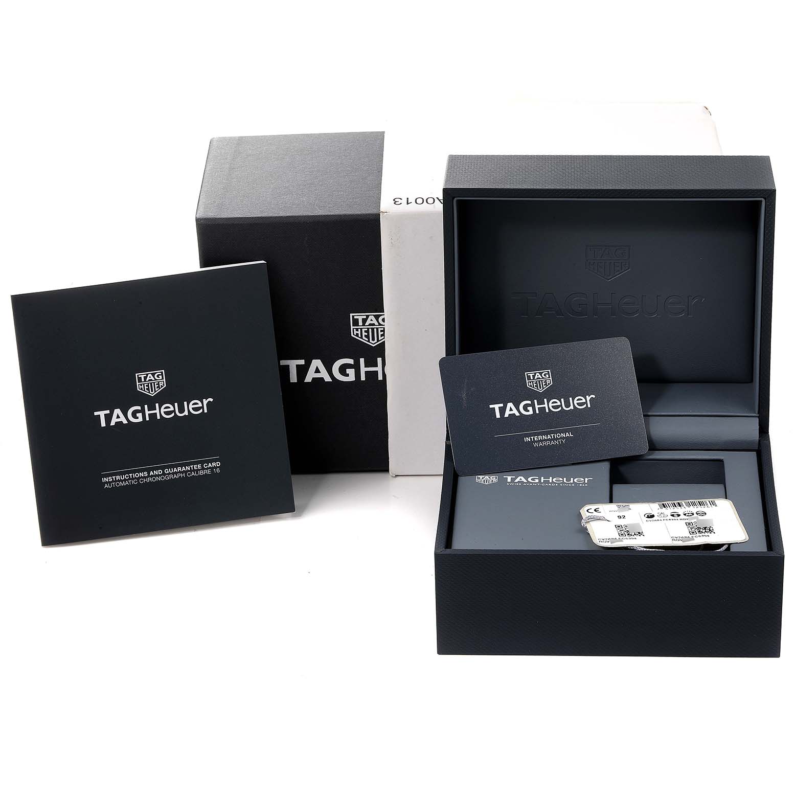 The image shows packaging and documentation for a Tag Heuer Carrera CV2A84.FC6394 Men
s Titanium Black Dial CV2A84.FC6394 Men
s Titanium Black Dial watch, including a box, warranty card, and instruction booklet.