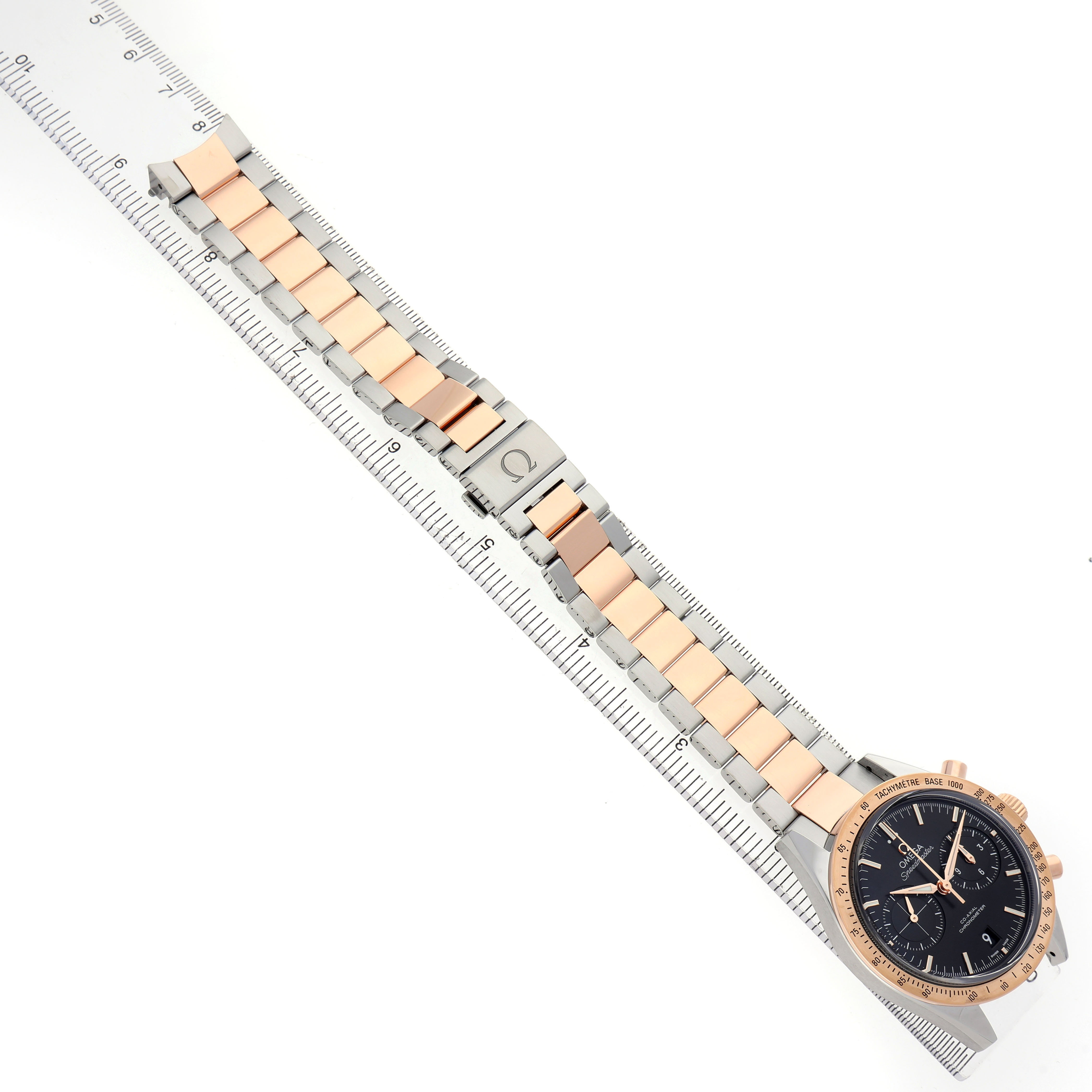 The Omega Speedmaster 331.20.42.51.01.002 Men's Rose Gold Black Dial is shown at an overhead angle, highlighting the watch face and two-tone metal band alongside a ruler.