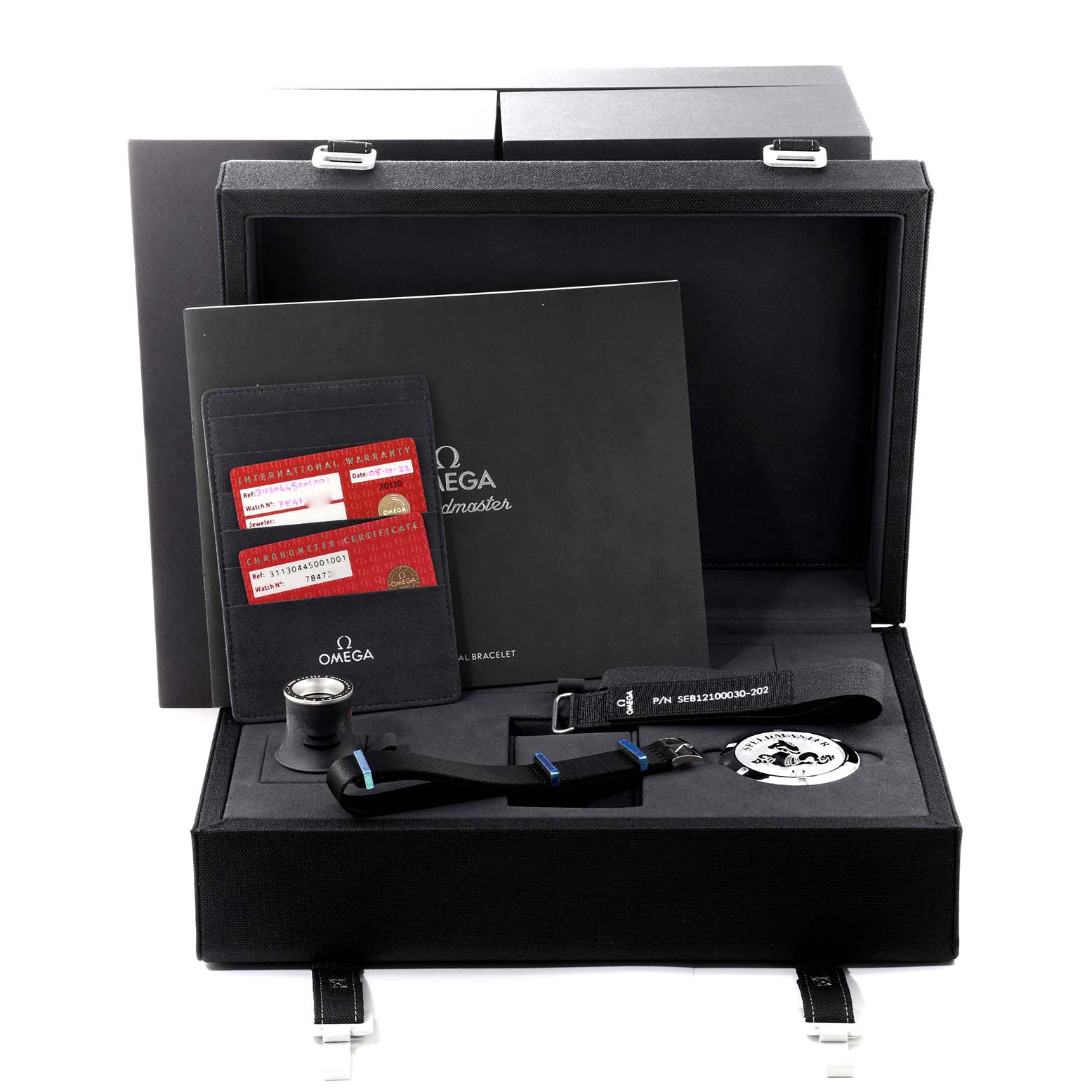 The image shows an Omega Speedmaster 311.30.44.50.01.001 Men's Stainless Steel Black Dial 311.30.44.50.01.001 Men's Stainless Steel Black Dial watch box with manuals, warranty cards, a loupe, and additional straps.