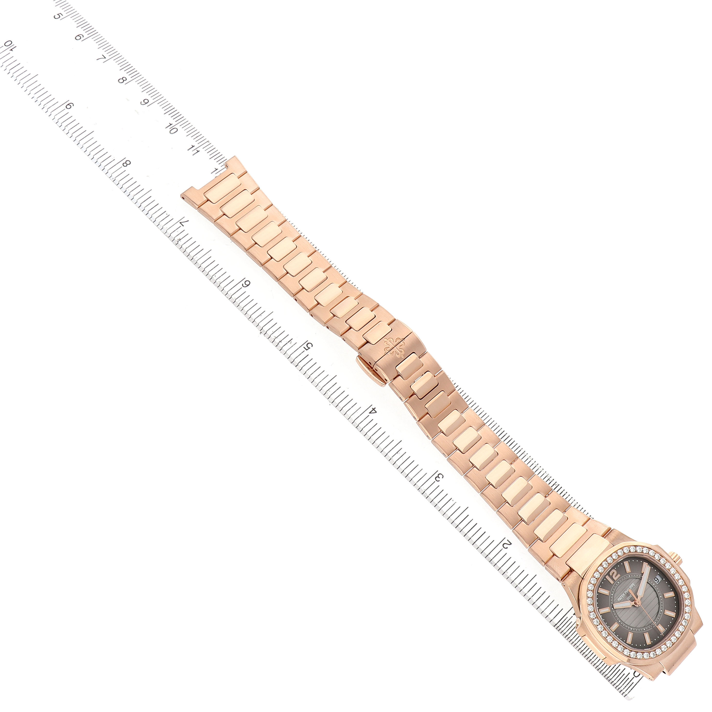 The Patek Philippe Nautilus 7010R Women's Rose Gold Brown Dial is shown laid flat at a slight angle, displaying the watch face, bracelet, and a ruler for scale.