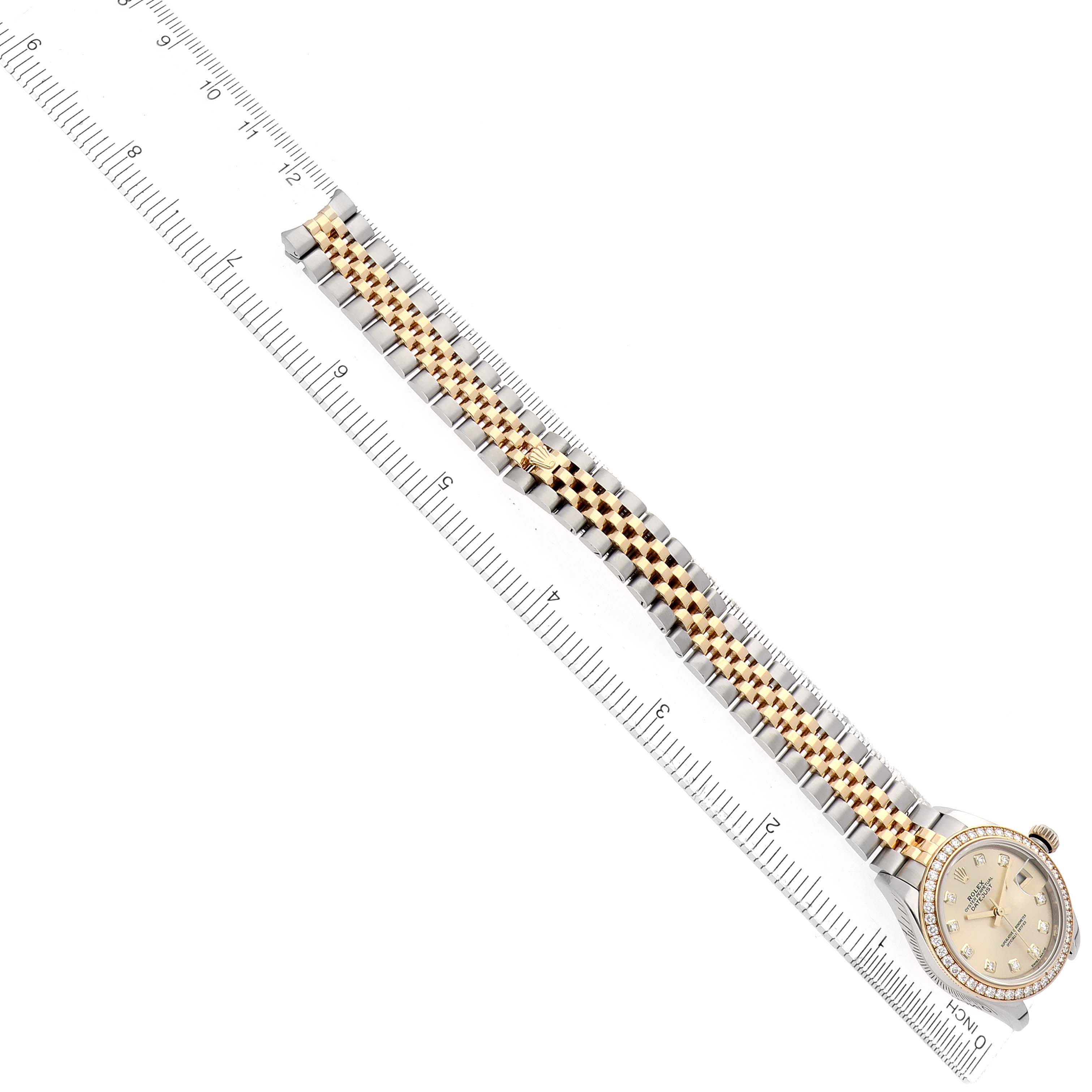 The Rolex Datejust 279383 Women
s Steel and Gold (two tone) Champagne Dial watch is shown diagonally, highlighting its full bracelet and face, alongside a ruler for scale.