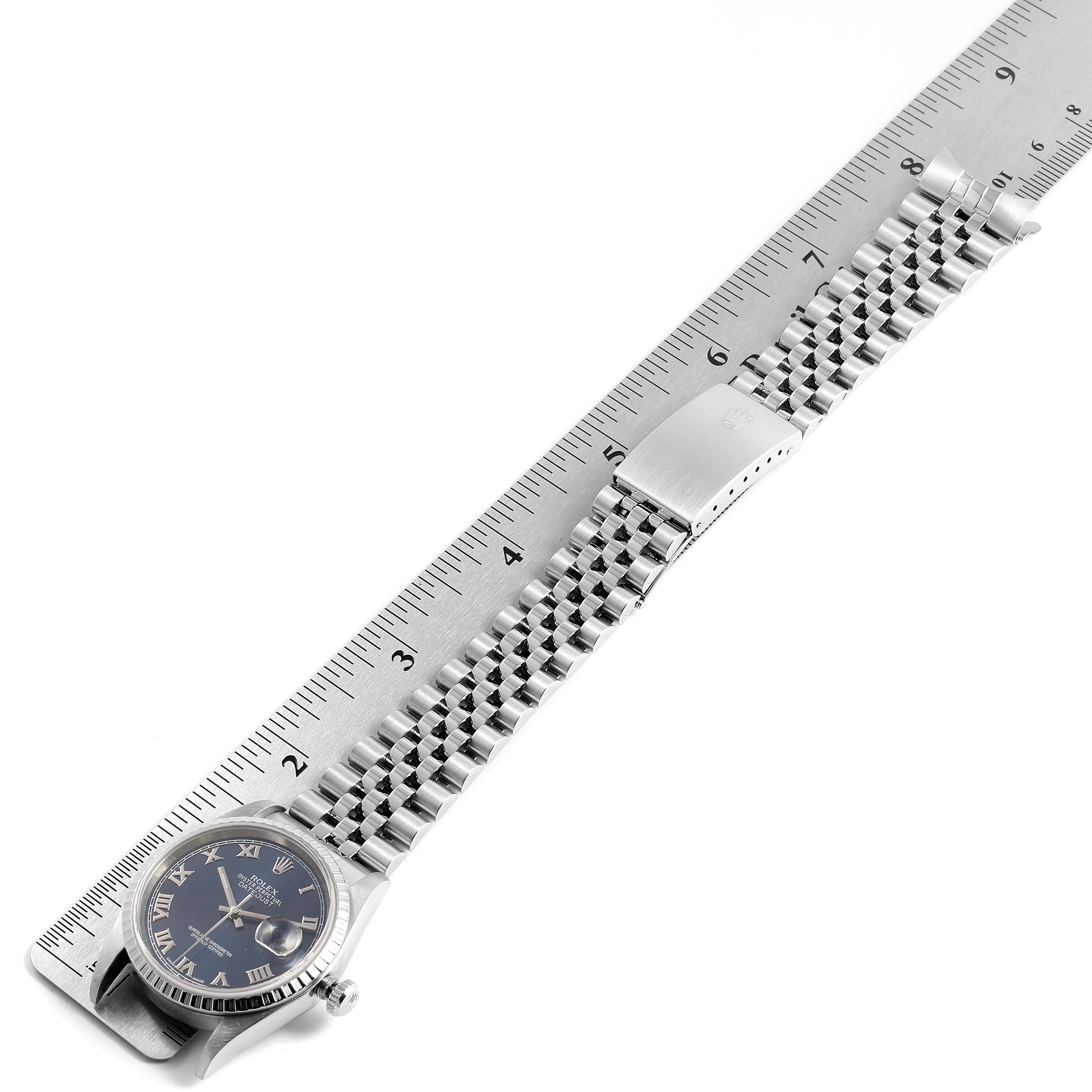 The image shows a Rolex Datejust 16220 Men
s Stainless Steel Blue Dial 16220 Men
s Stainless Steel Blue Dial watch lying flat next to a ruler, displaying the face and metal bracelet.