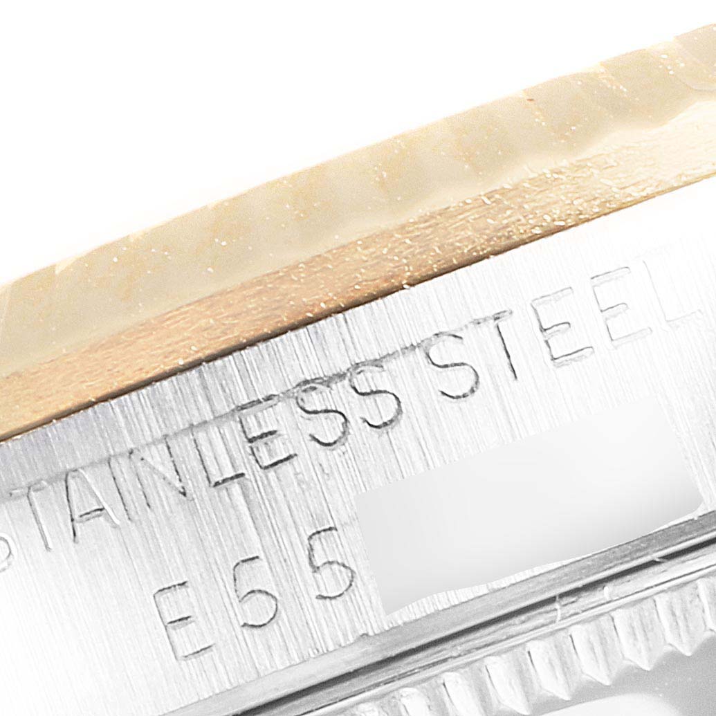 The image shows a close-up of the bezel and part of the casing of a Rolex Mid-Size 68273 Women
s Steel and Gold (two tone) Champagne Dial 68273 Women
s Steel and Gold (two tone) Champagne Dial model watch, featuring "Stainless Steel" engraving.