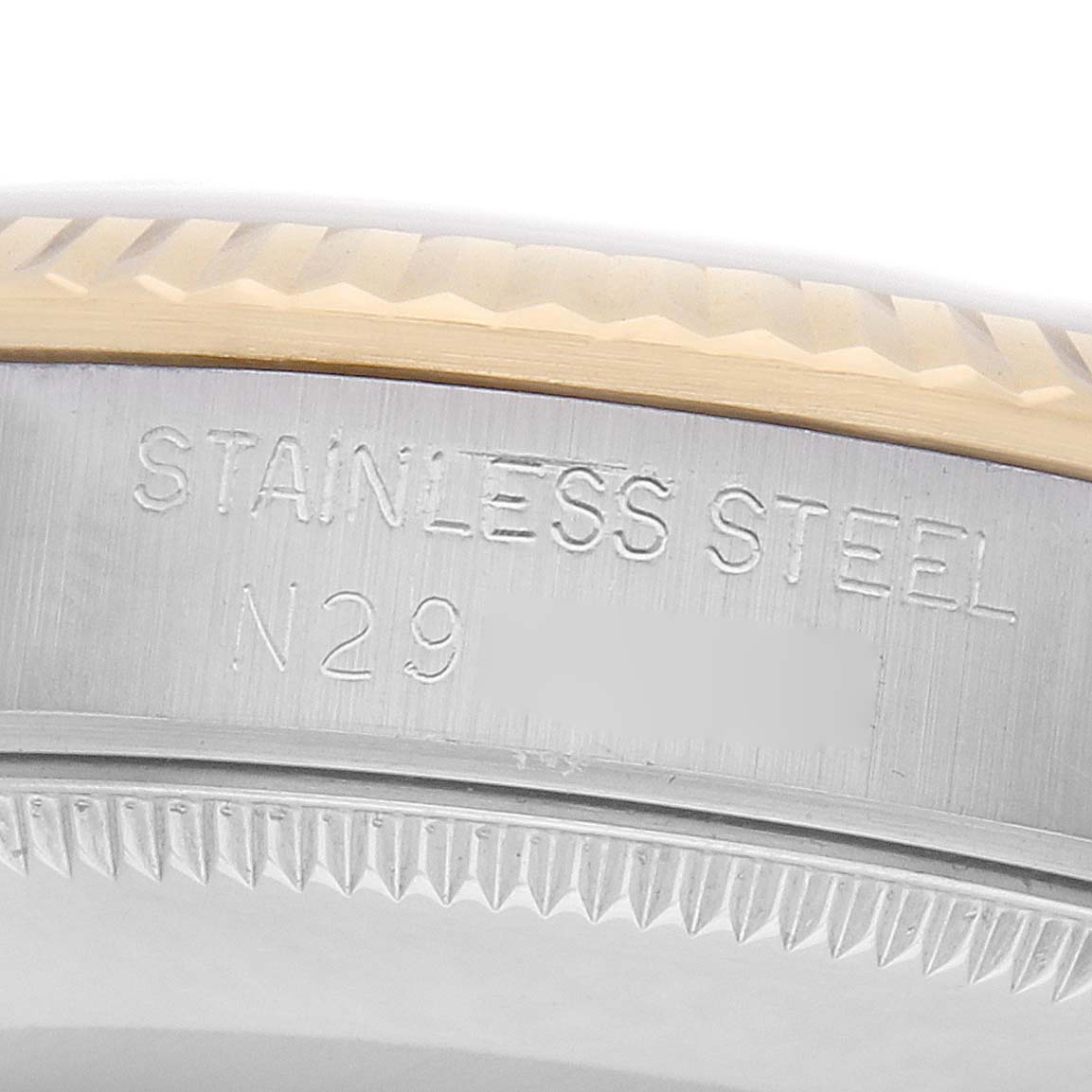 The image shows a close-up of the side edge of a Rolex Mid-Size 68273 Women
s Steel and Gold (two tone) Champagne Dial watch, highlighting the stainless steel and engraved markings.