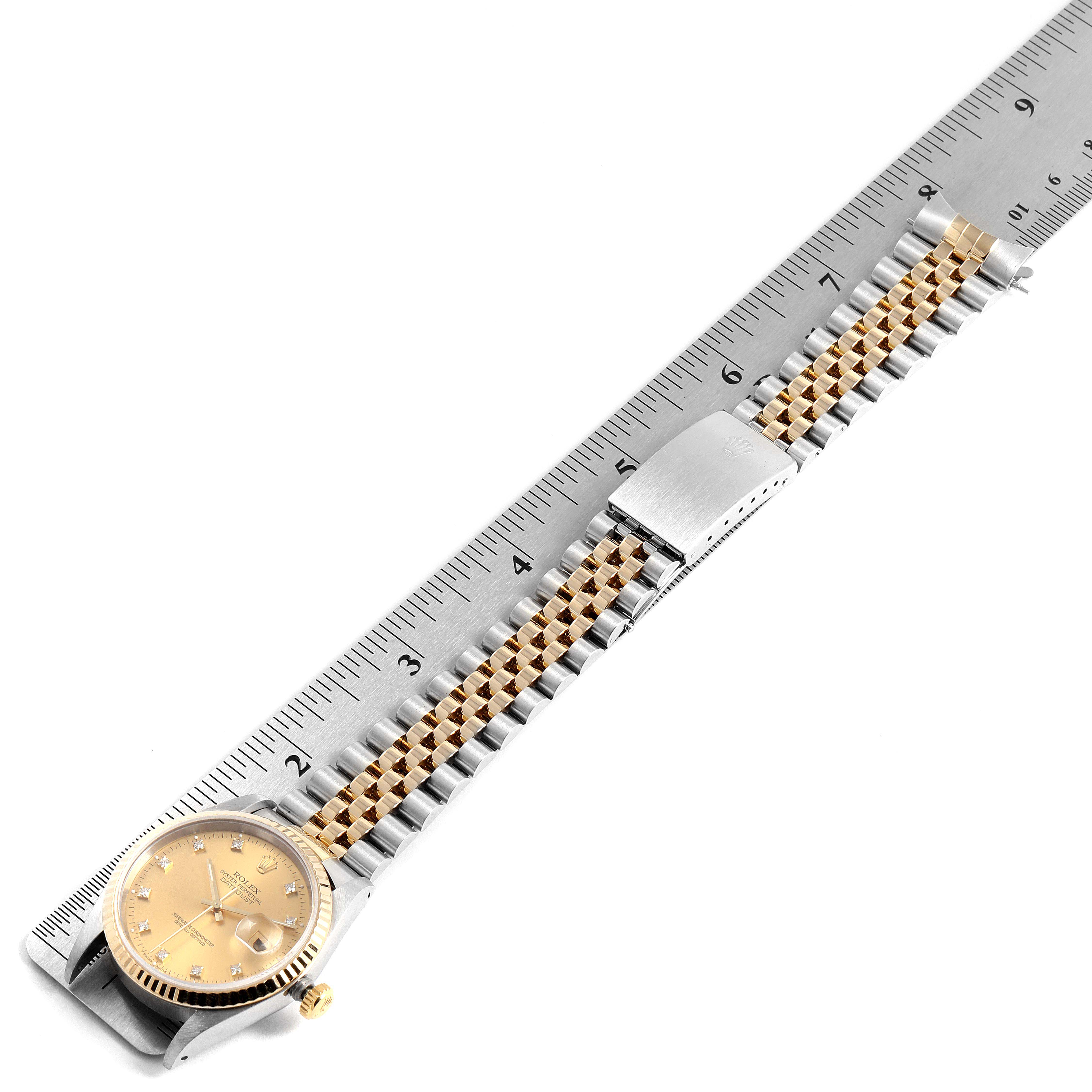 The image shows a Rolex Datejust 16233 Men
s Steel and Gold (two tone) Champagne Dial 16233 Men
s Steel and Gold (two tone) Champagne Dial watch from a top view, displaying the face, clasp, and bracelet next to a ruler.