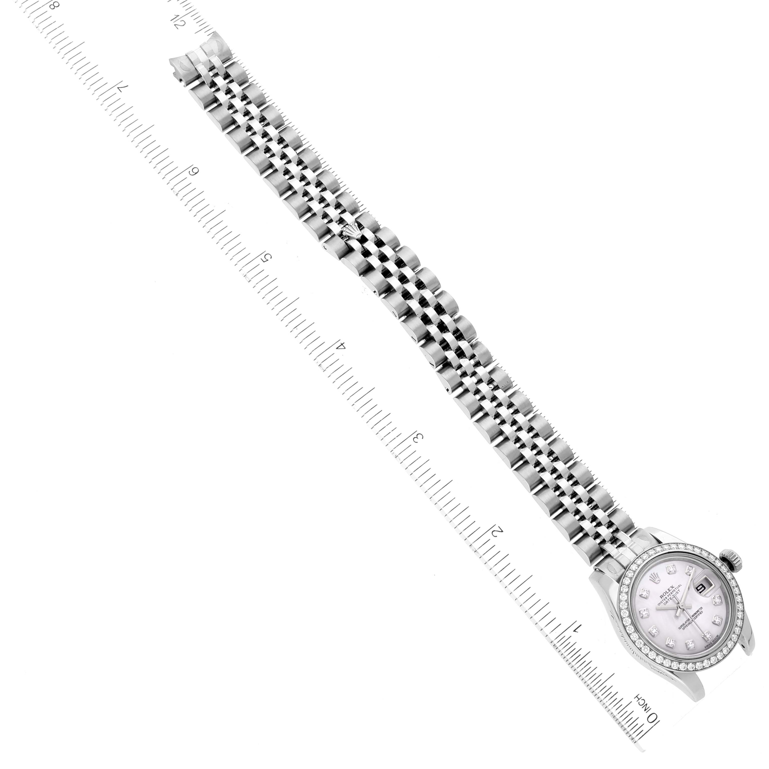 The image shows a top-down view of the Rolex Datejust 179384 Women
s Stainless Steel Mother of Pearl Dial 179384 Women
s Stainless Steel Mother of Pearl Dial watch with an extended bracelet next to a ruler for scale.