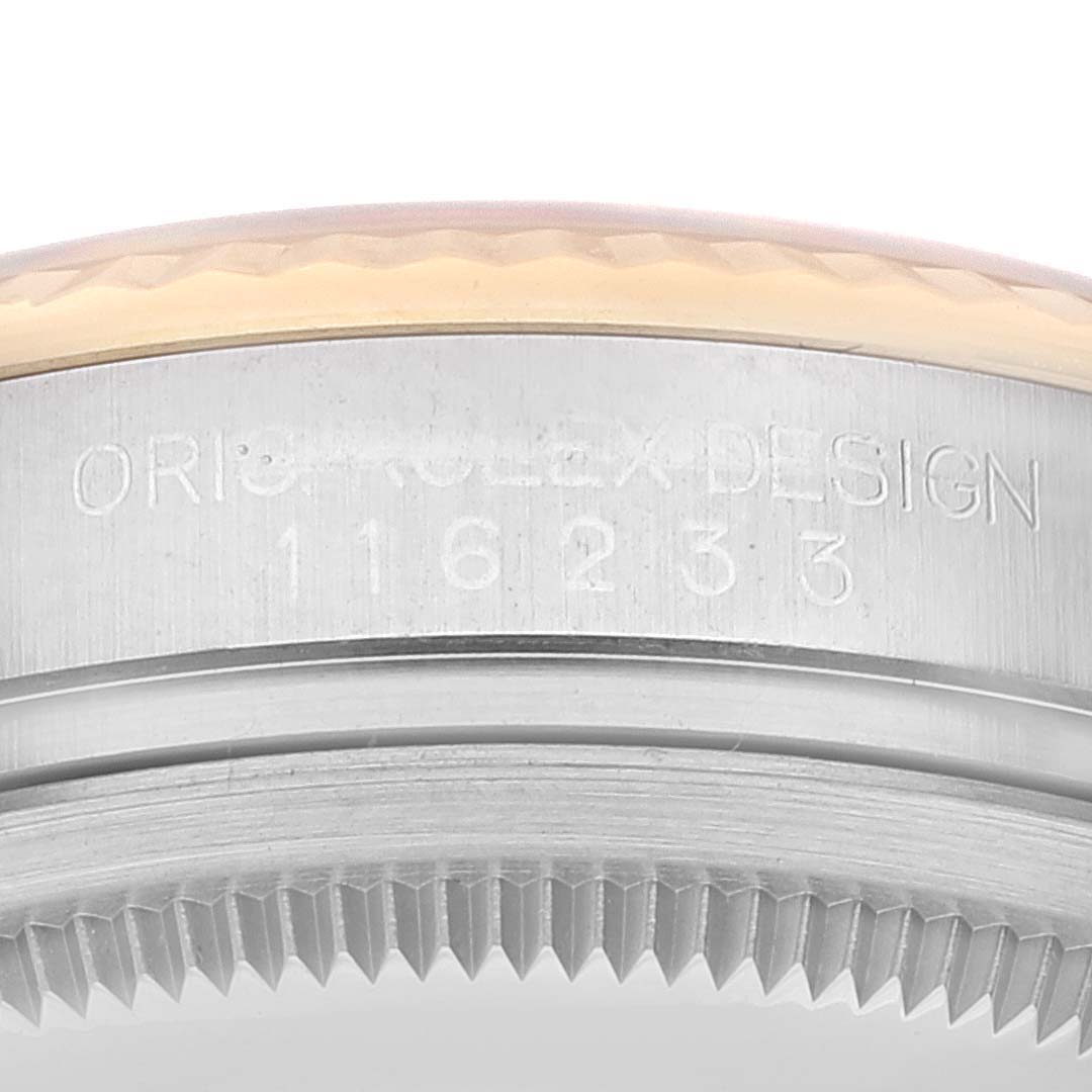 This image shows a close-up of the side of a Rolex Datejust 116233 Men's Steel and Gold (two tone) Champagne Dial 116233 Men's Steel and Gold (two tone) Champagne Dial watch, detailing the model number 116233 and "ORIG ROLEX DESIGN" engraving.