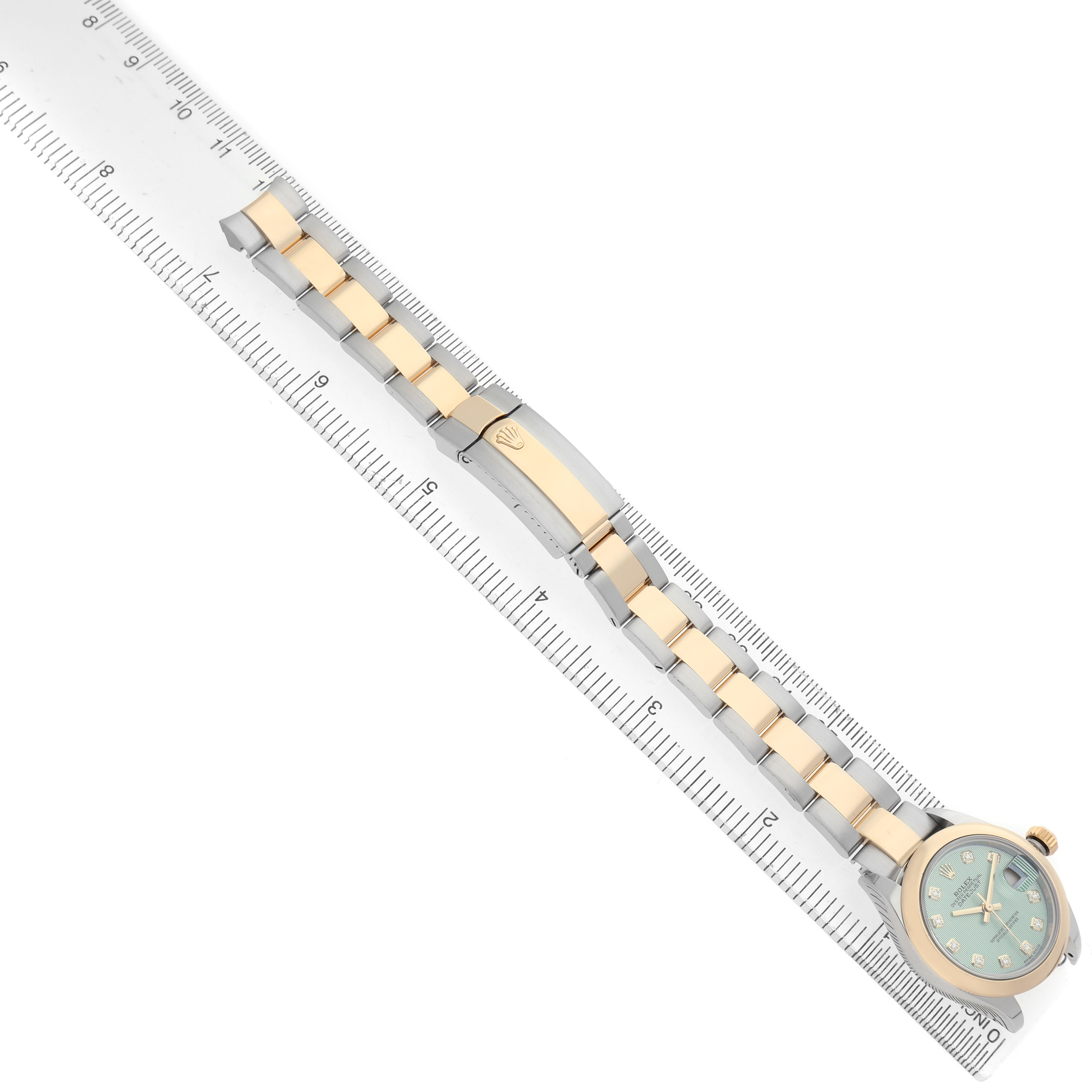 The image shows a top view of a Rolex Datejust 279163 Women's Steel and Gold (two tone) Green Dial watch with its bracelet and clasp aligned alongside a ruler.