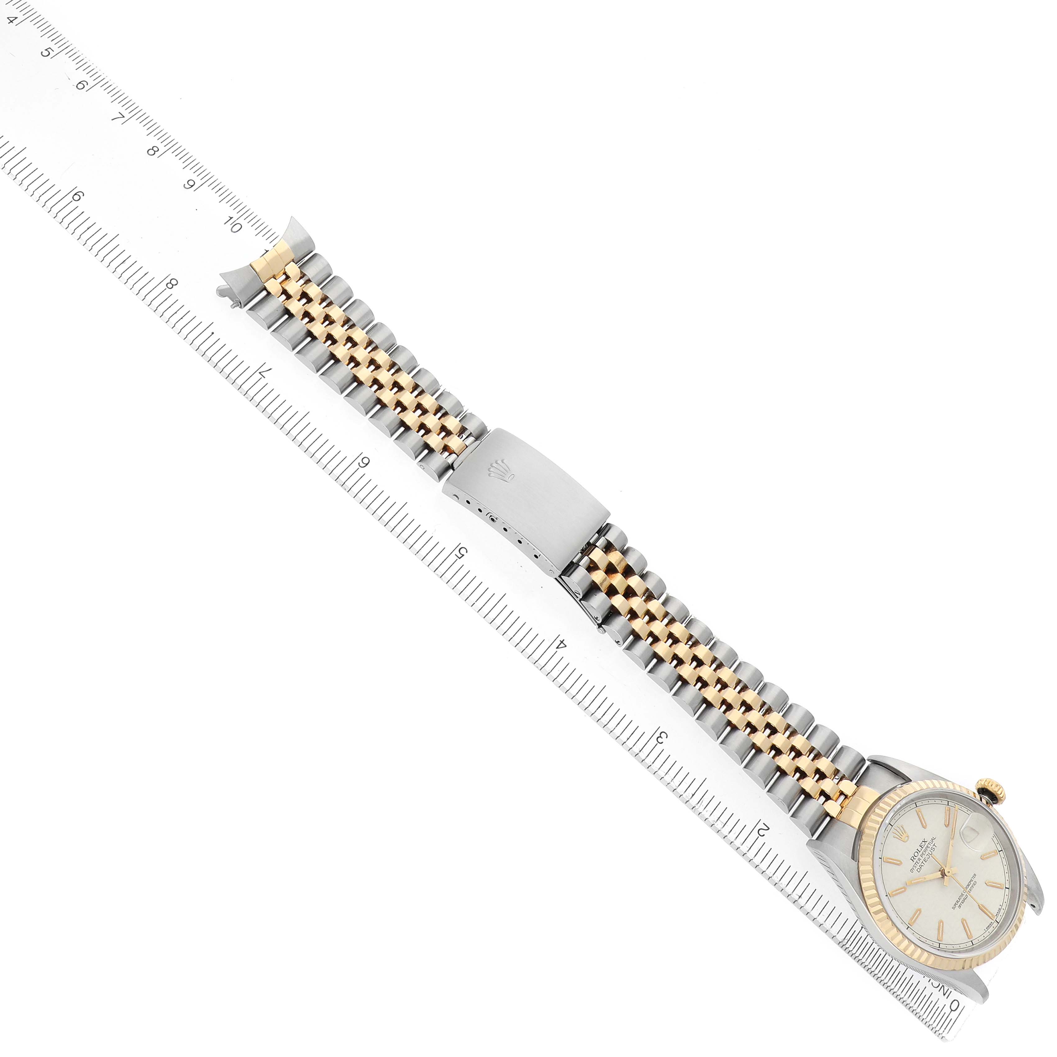 The Rolex Datejust 16233 Men
s Steel and Gold (two tone) Beige Dial watch is shown at a diagonal angle with its band and clasp visible, alongside a ruler for scale.
