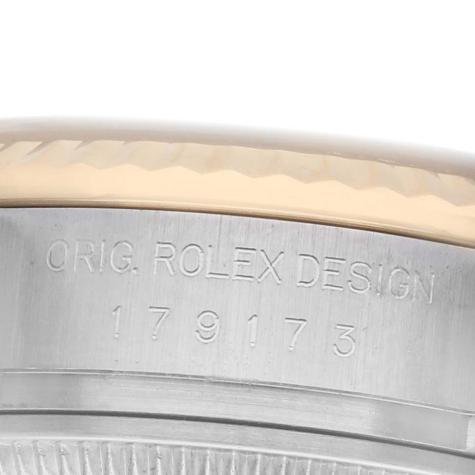 The image shows a close-up of the Rolex Datejust 179173 Women
s Steel and Gold (two tone) Red Dial model
s case side, focusing on the engraved serial and model numbers.