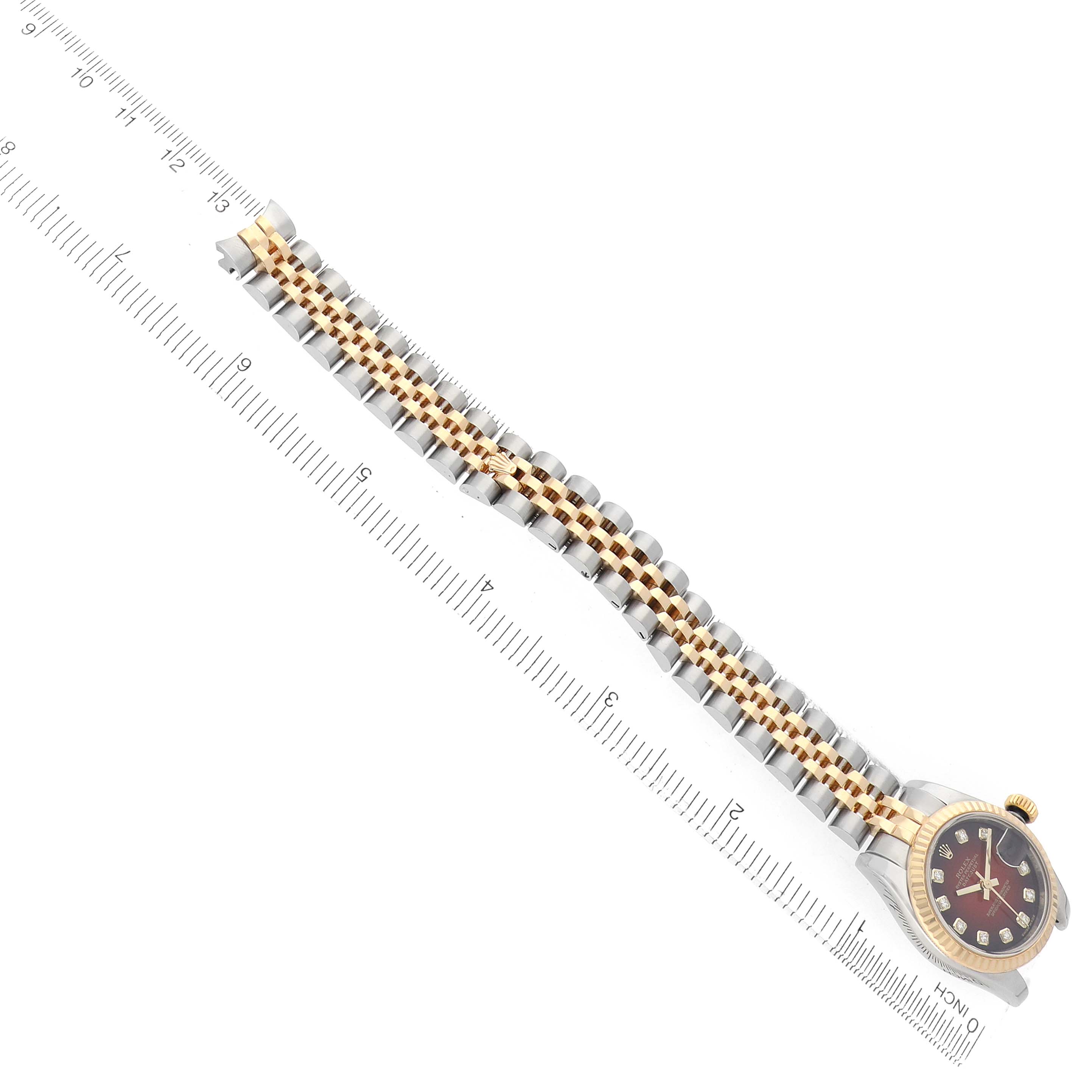 The Rolex Datejust 179173 Women
s Steel and Gold (two tone) Red Dial watch is shown laid flat with its bracelet and case visible alongside a ruler for scale.