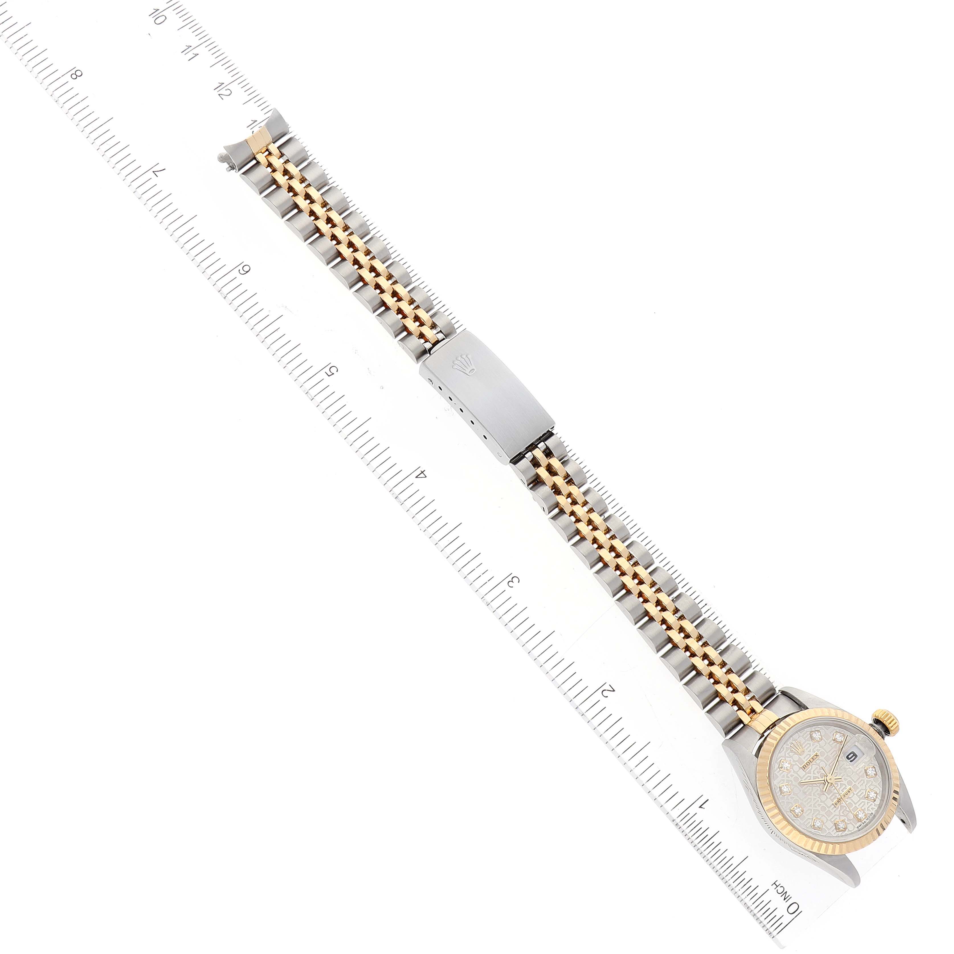 The Rolex Datejust 79173 Women's Steel and Gold (two tone) Silver Dial 79173 Women's Steel and Gold (two tone) Silver Dial watch is shown flat with its bracelet and clasp fully extended next to a ruler for scale.