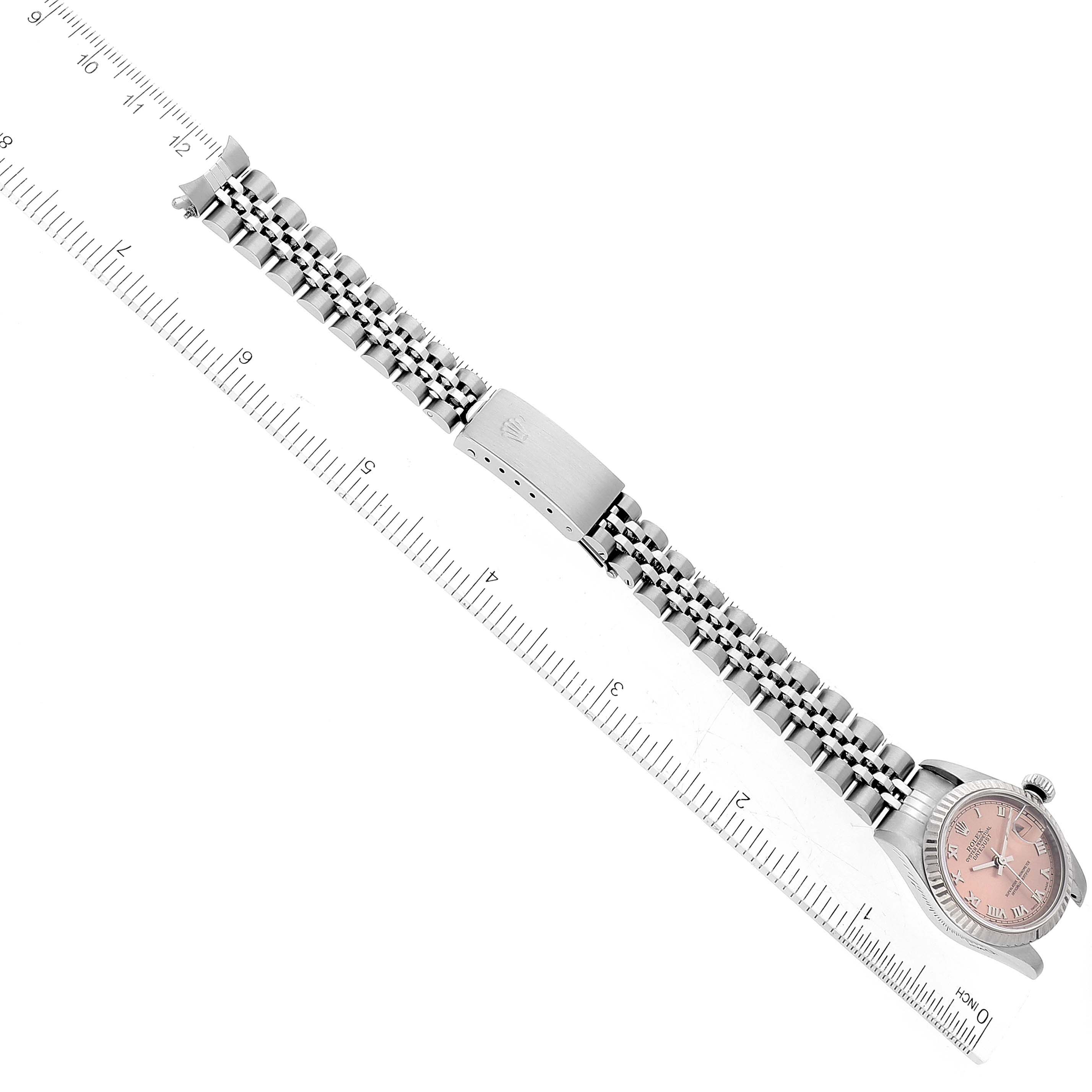 This image shows the full view of a Rolex Datejust 79174 Women's Stainless Steel Orange Dial 79174 Women's Stainless Steel Orange Dial watch with a stainless steel bracelet, placed adjacent to a ruler for size reference.