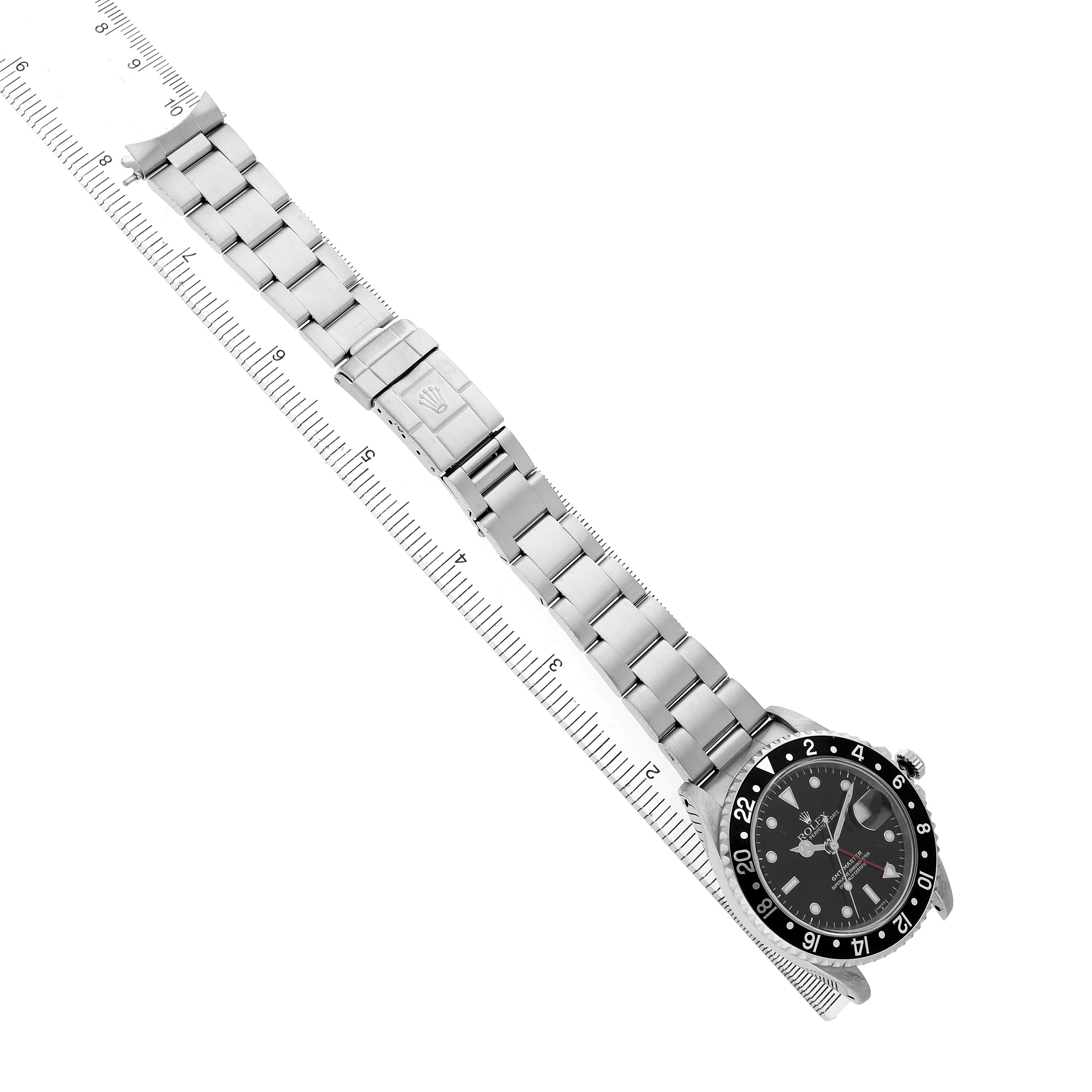 The Rolex GMT-Master 16700 Men's Stainless Steel Black Dial watch is shown at a diagonal angle, displaying the full bracelet and face next to a ruler.